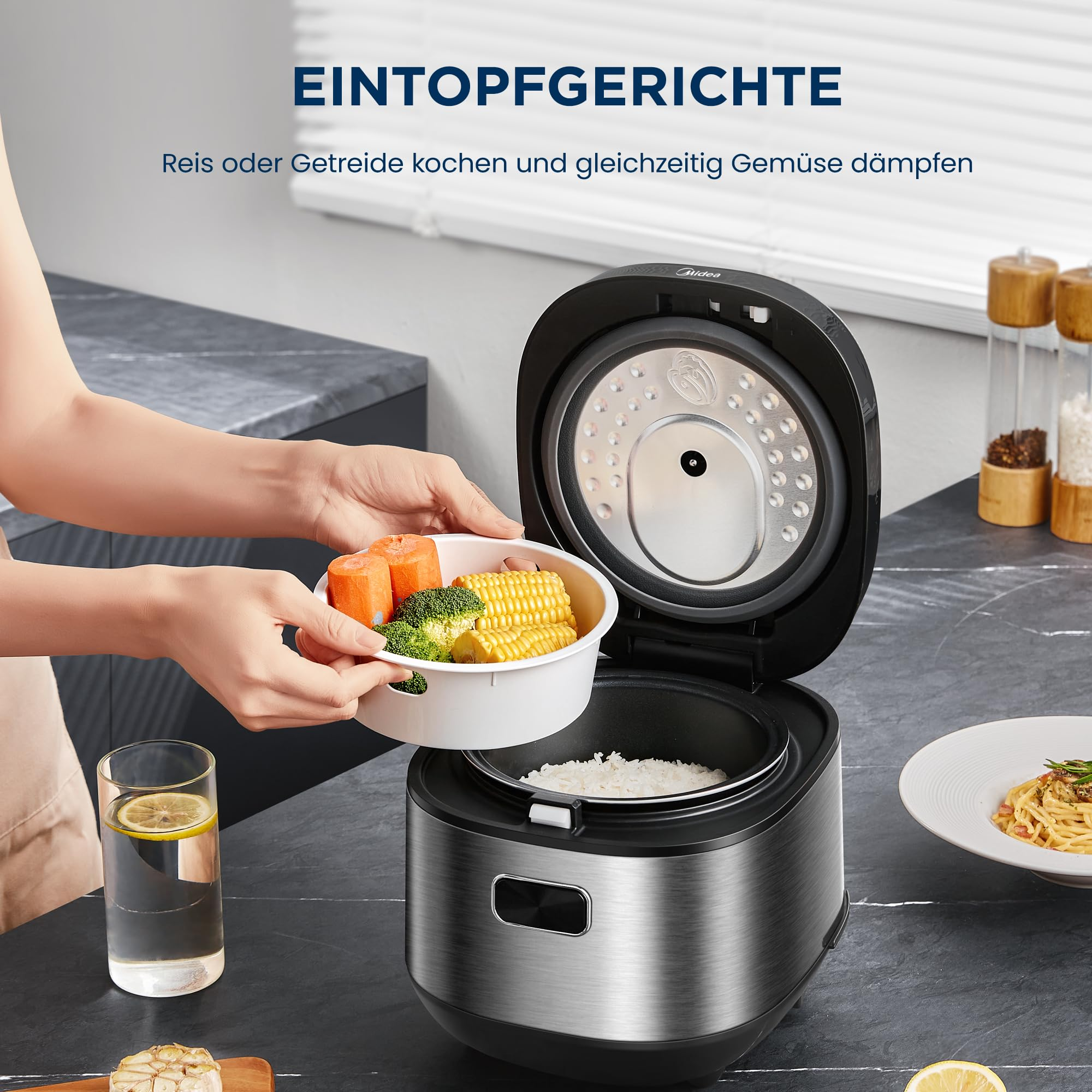 Eine Person stellt eine Schüssel mit Gemüse über kochenden Reis in einen offenen Reiskocher auf einer Küchenarbeitsplatte.
