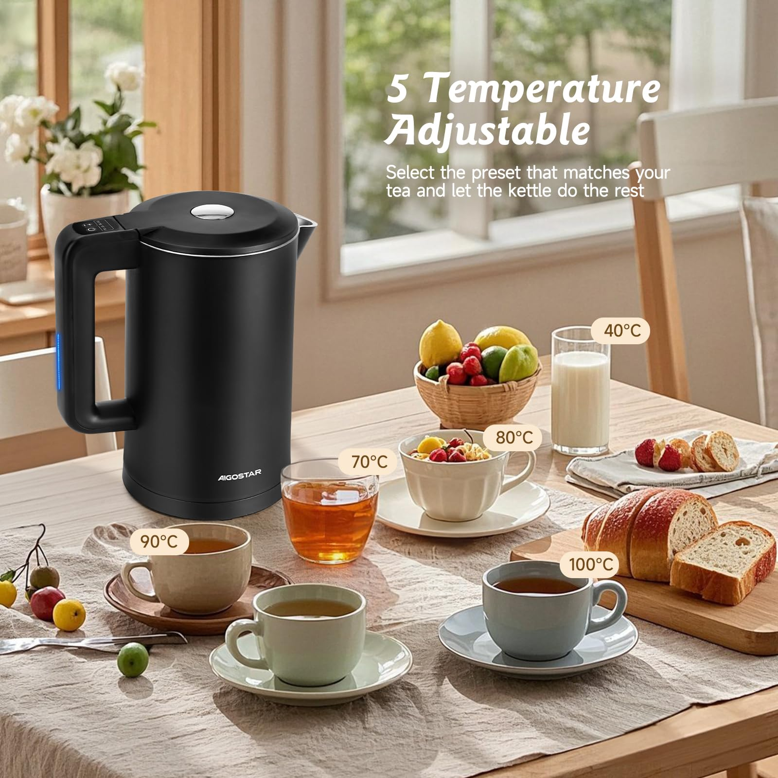 Une bouilloire électrique noire sur une table en bois avec des tasses de thé, des fruits et du pain.