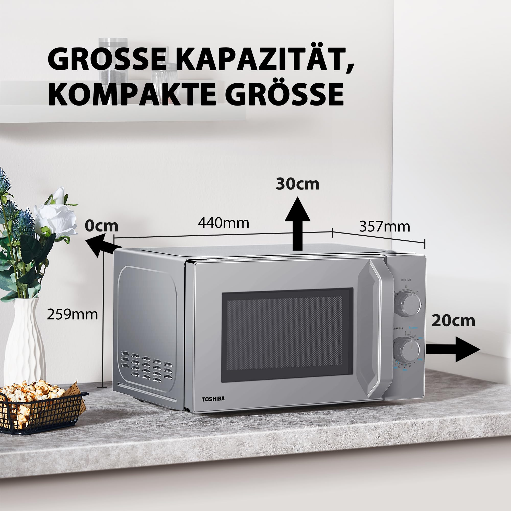 Silberne Toshiba Mikrowelle auf einer Arbeitsplatte mit Maßangaben.