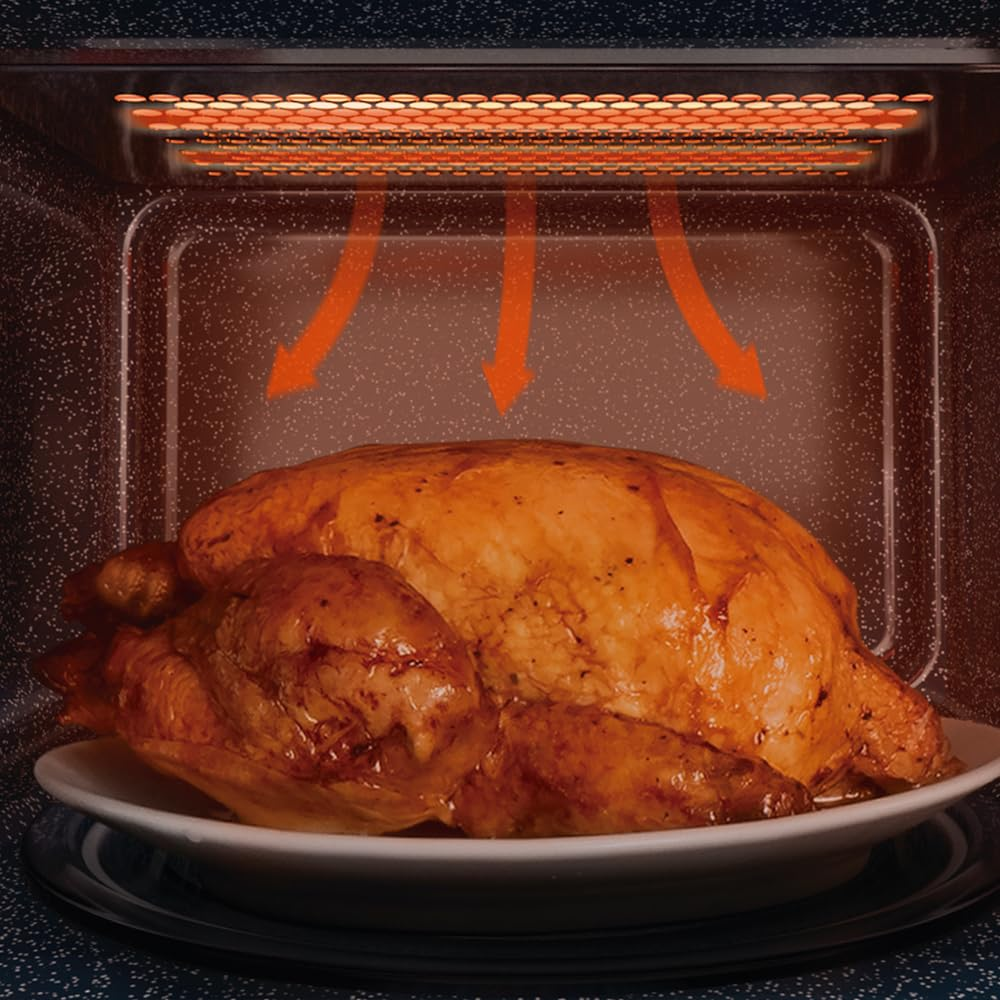 Un poulet rôti entier sur une assiette à l'intérieur d'un four éclairé.