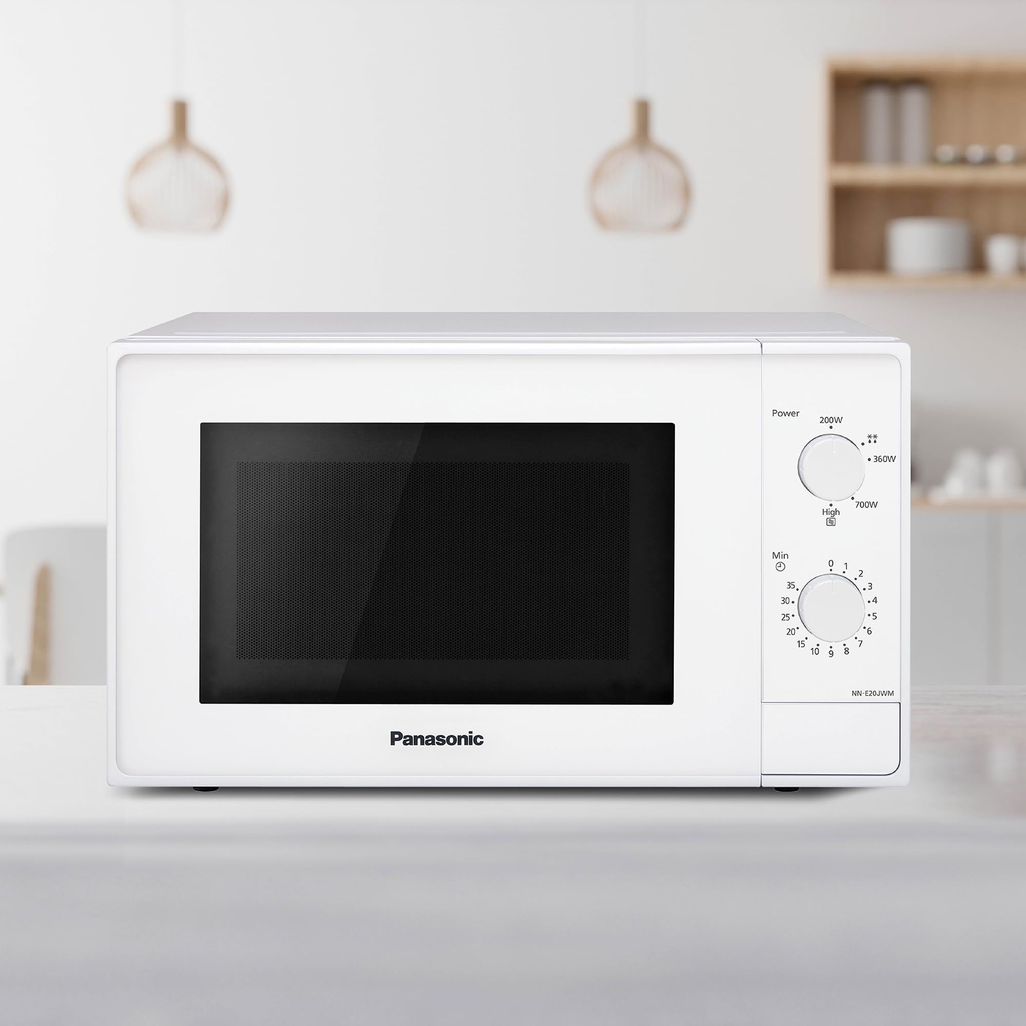 Eine weiße Panasonic Mikrowelle steht auf einer Arbeitsplatte in einer hellen Küche mit verschwommenem Hintergrund.
