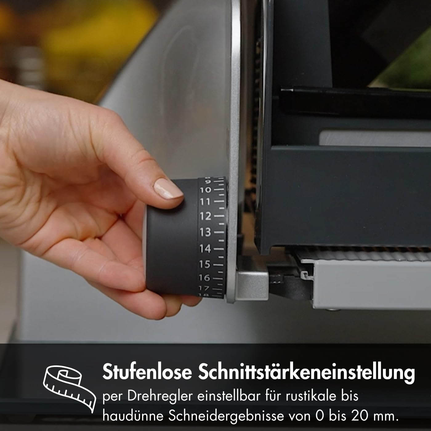 Eine Hand verstellt das Rad einer Aufschnittmaschine mit nummerierten Stufen.