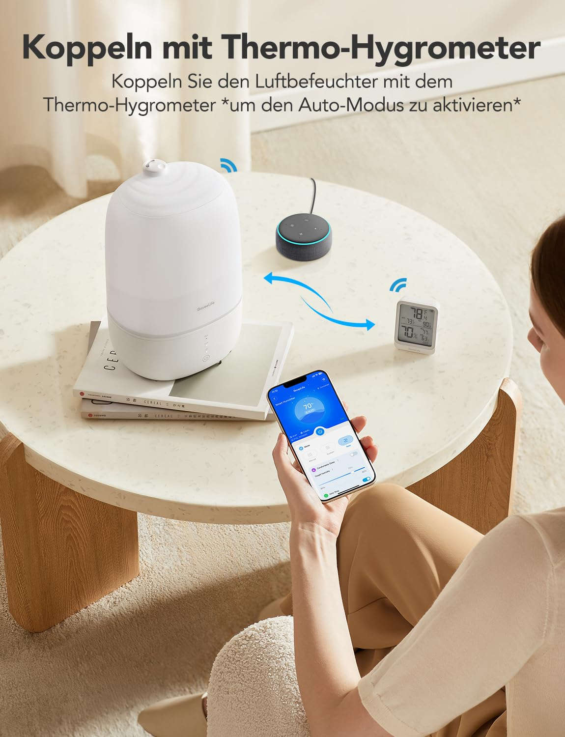Una donna usa un'app per smartphone per controllare un umidificatore bianco e un igrometro.