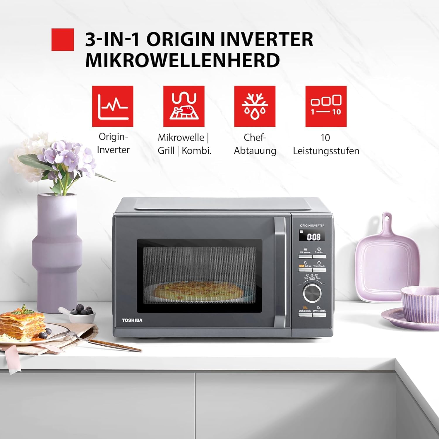 Micro-ondes gris Toshiba sur un comptoir avec fleurs, vaisselle et icônes de fonctionnalités.