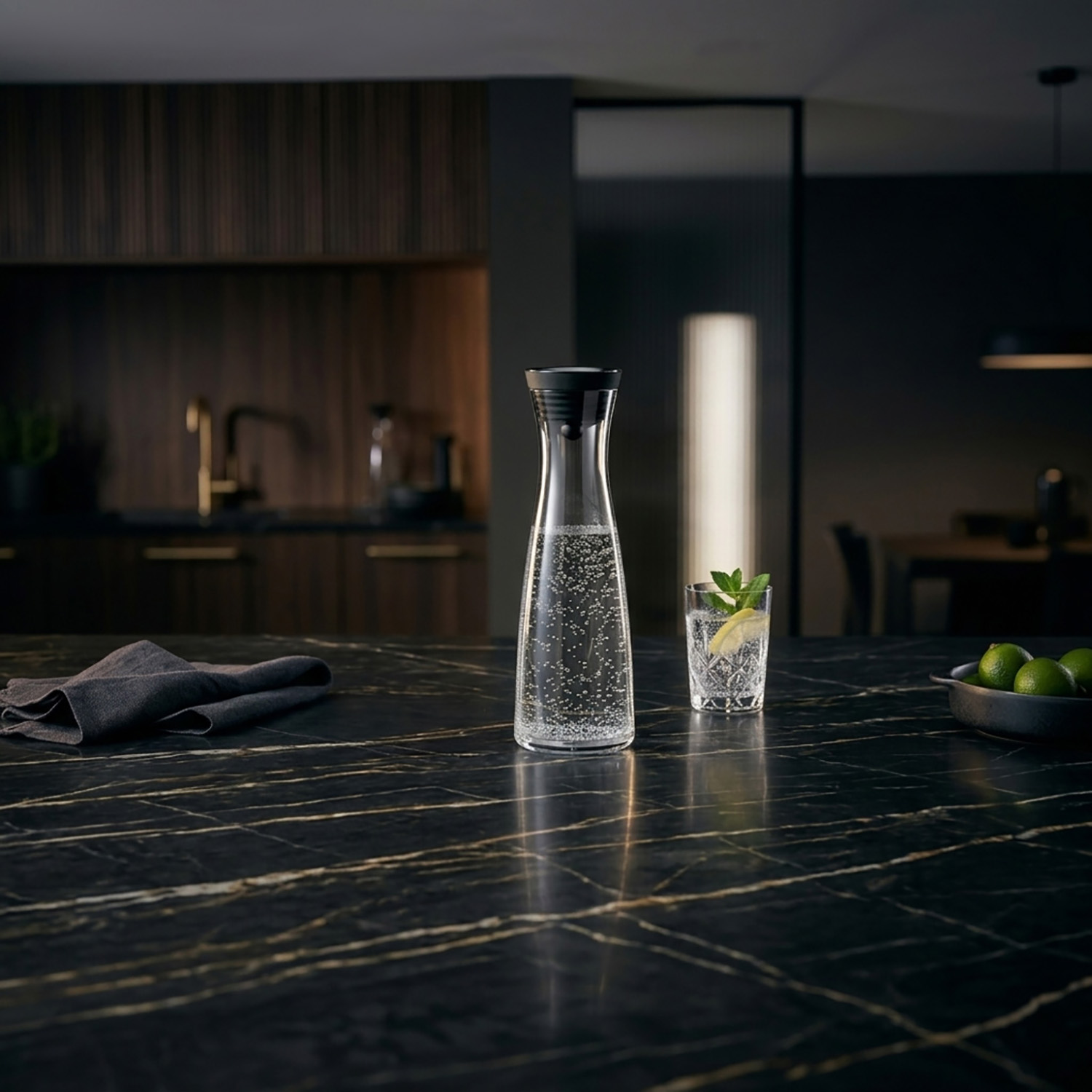 Wasserkaraffe mit Blasen und Glas Wasser mit Zitrone und Minze auf dunkler Marmortheke.