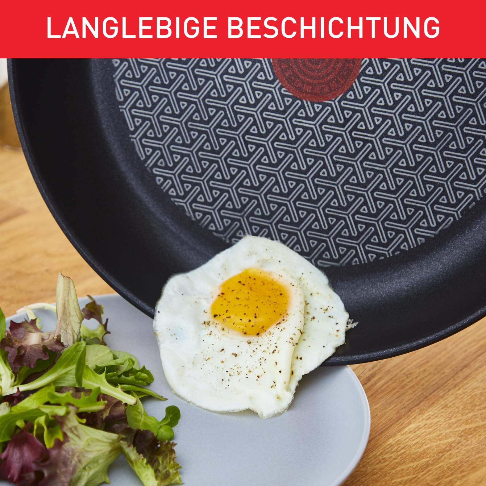 Un oeuf au plat glisse d'une poêle antiadhésive vers une assiette de salade.