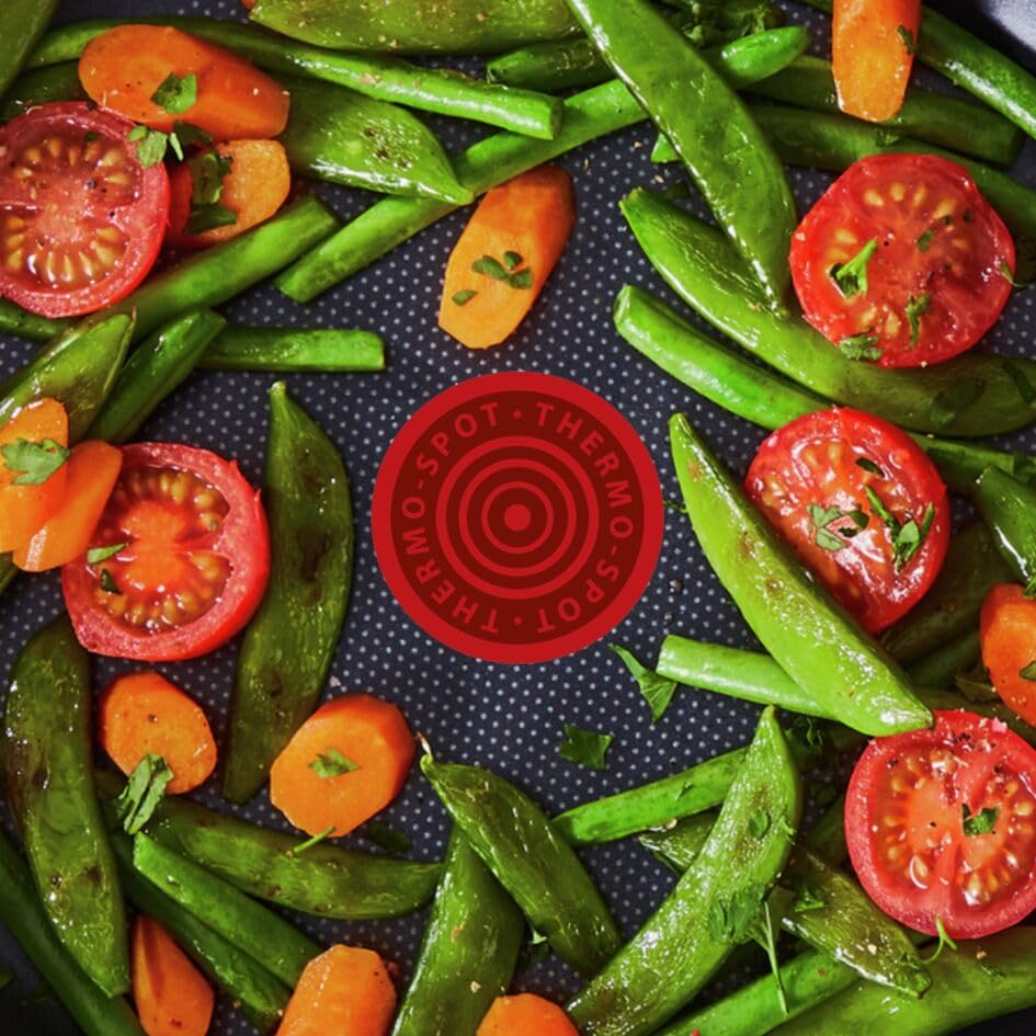 Haricots verts, rondelles de carottes et tomates dans une poêle.