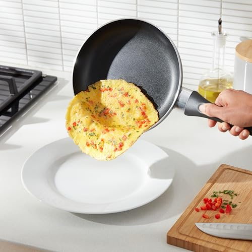 Una frittata scivola da una padella a un piatto bianco in una cucina.