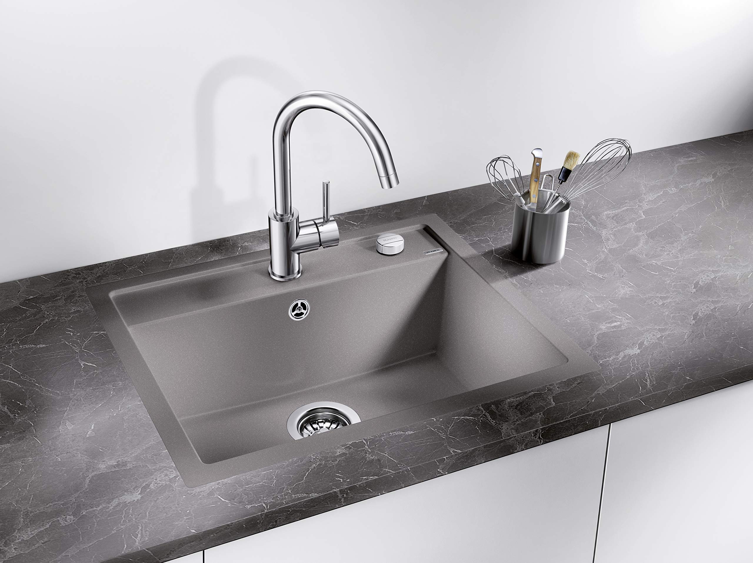 Graue Küchenspüle mit chromfarbenem Wasserhahn auf einer Marmorarbeitsplatte.