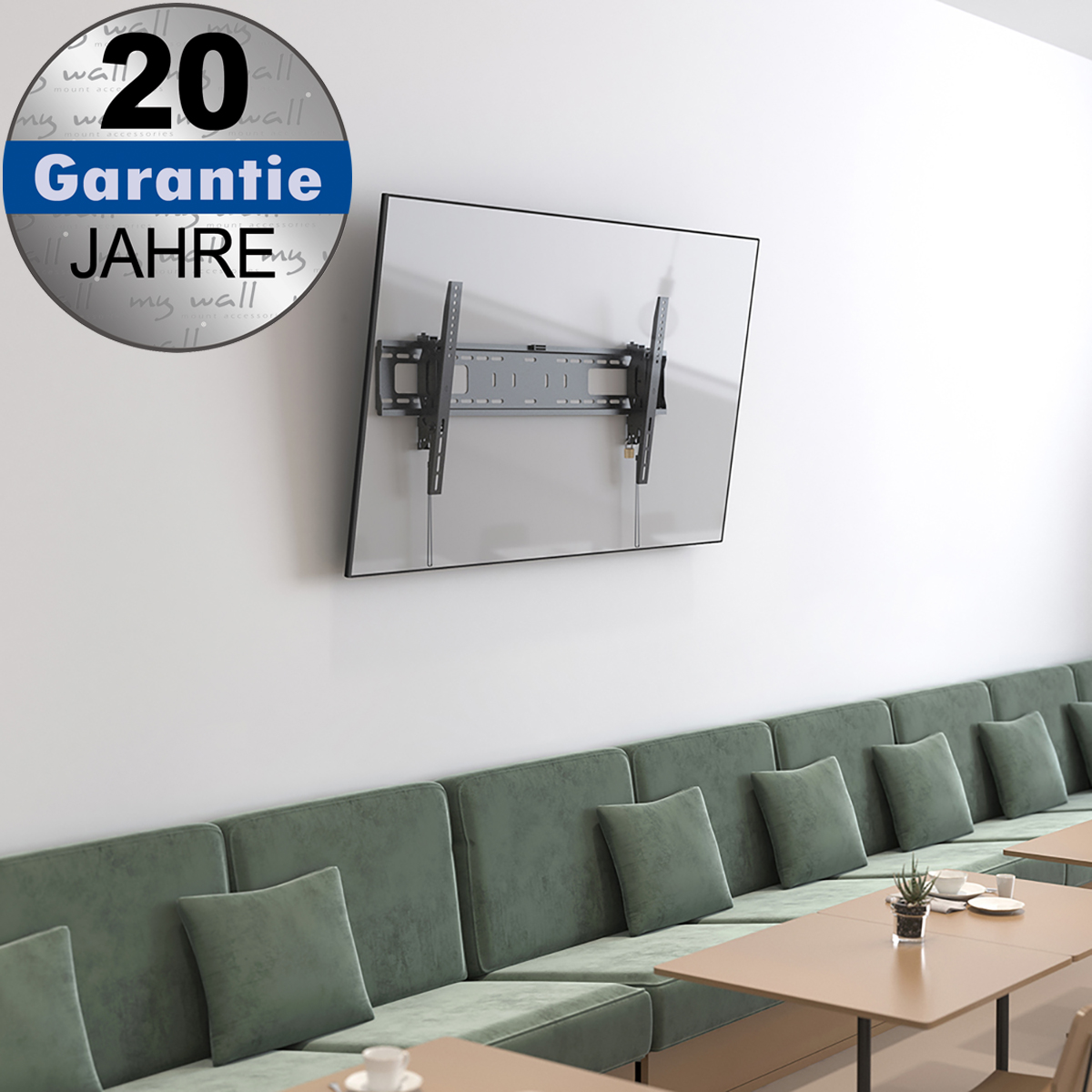 Ein TV-Wandhalter montiert an einer Wand über einer grünen Sitzbank mit Kissen und Tischen.