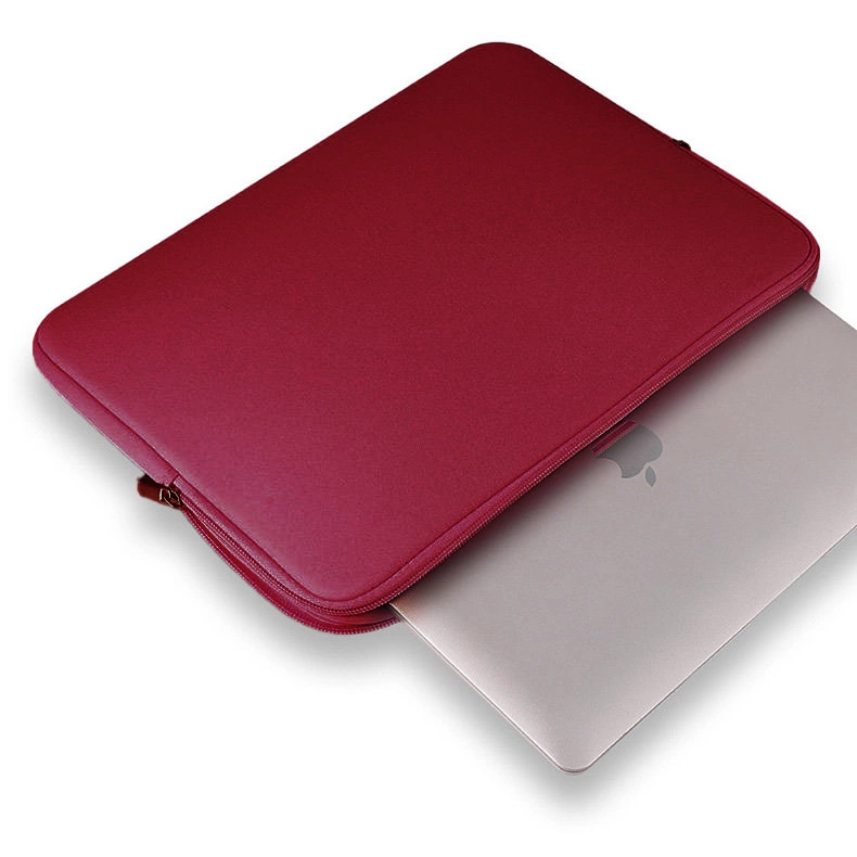 Una custodia rossa per laptop su sfondo bianco con un laptop argentato parzialmente inserito.