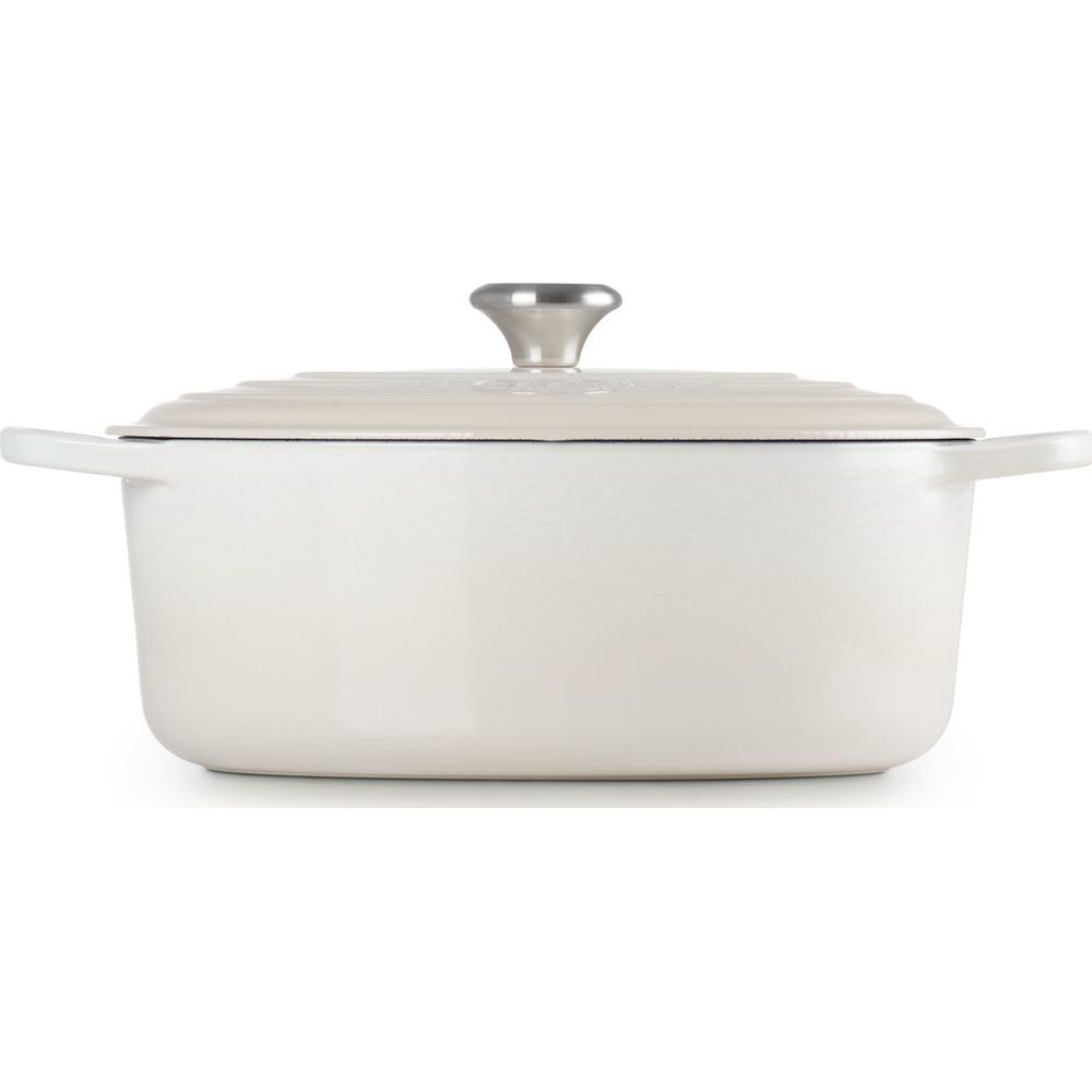 Une cocotte en fonte beige avec couvercle assorti et bouton métallique sur fond blanc.