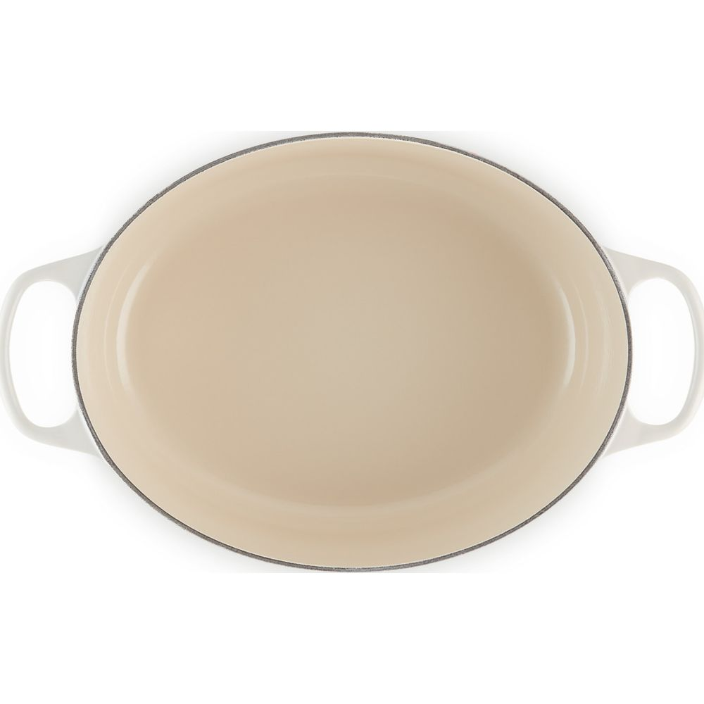 Un plat à rôtir ovale blanc avec un intérieur beige et deux poignées latérales.
