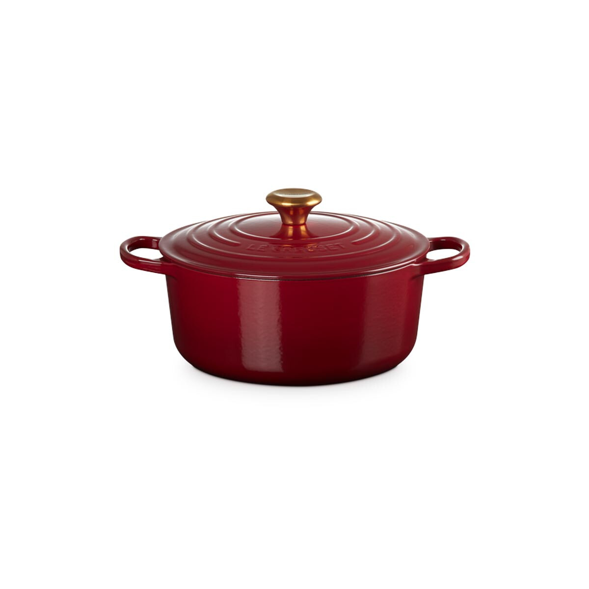 Une cocotte en fonte rouge brillante avec deux poignées et un bouton doré sur le couvercle sur fond blanc.