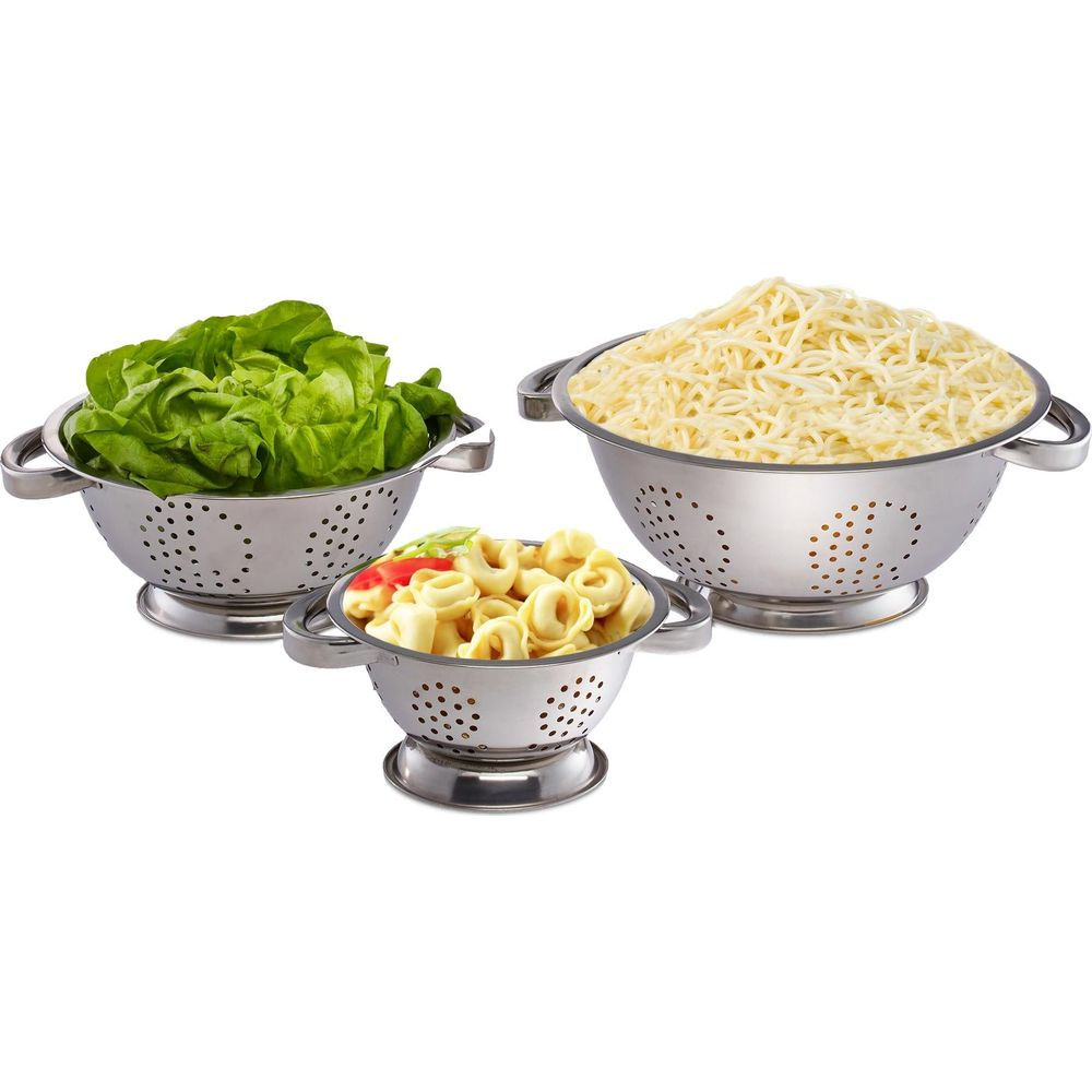 Drei Edelstahl-Siebe gefüllt mit grünem Salat, Spaghetti und Tortellini vor weißem Hintergrund.