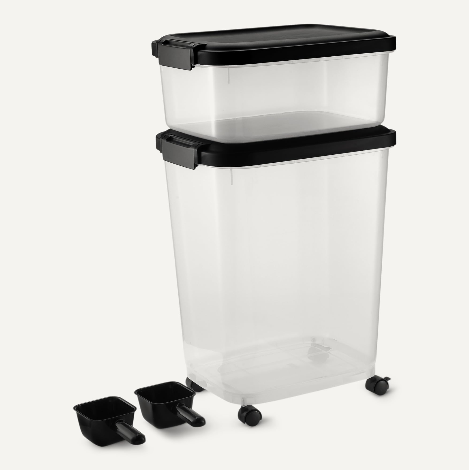 Due contenitori di plastica trasparente con coperchi e ruote neri, accompagnati da due piccoli misurini.