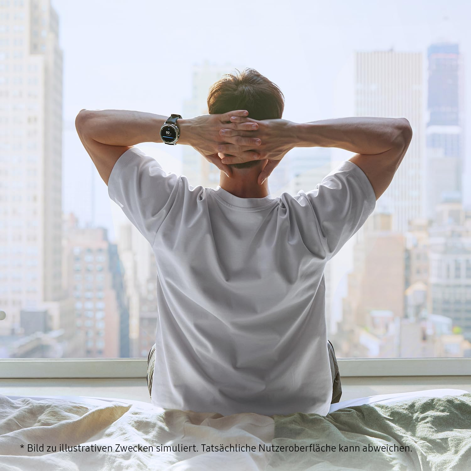 Un homme en t-shirt blanc assis sur le lit, mains derrière la nuque, regarde la ville.