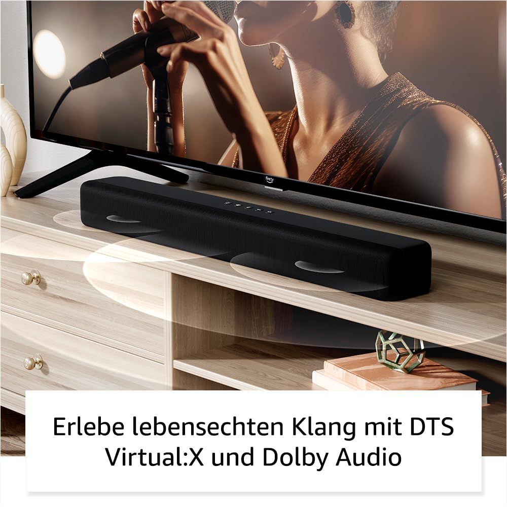 Schwarze Soundbar auf einem Holzschrank vor einem Fernseher, der eine Sängerin zeigt.