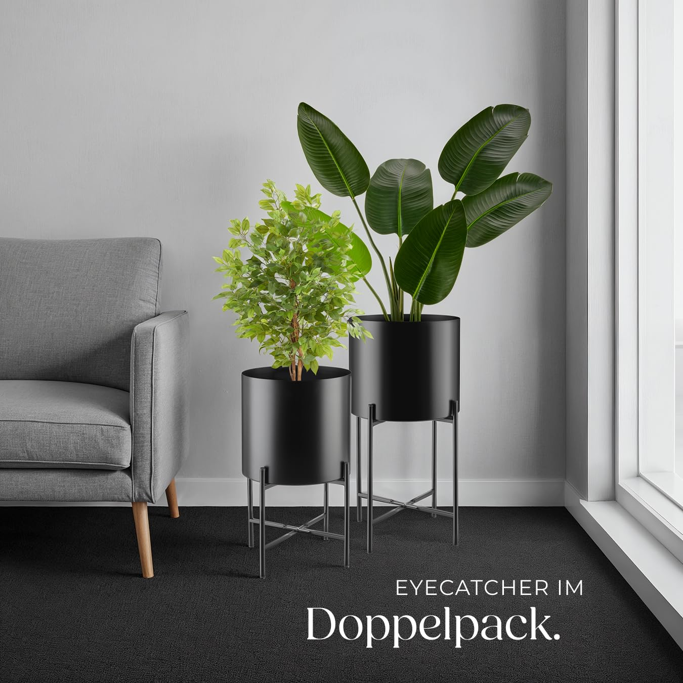 Deux plantes d'intérieur dans des supports métalliques noirs à côté d'un fauteuil gris.