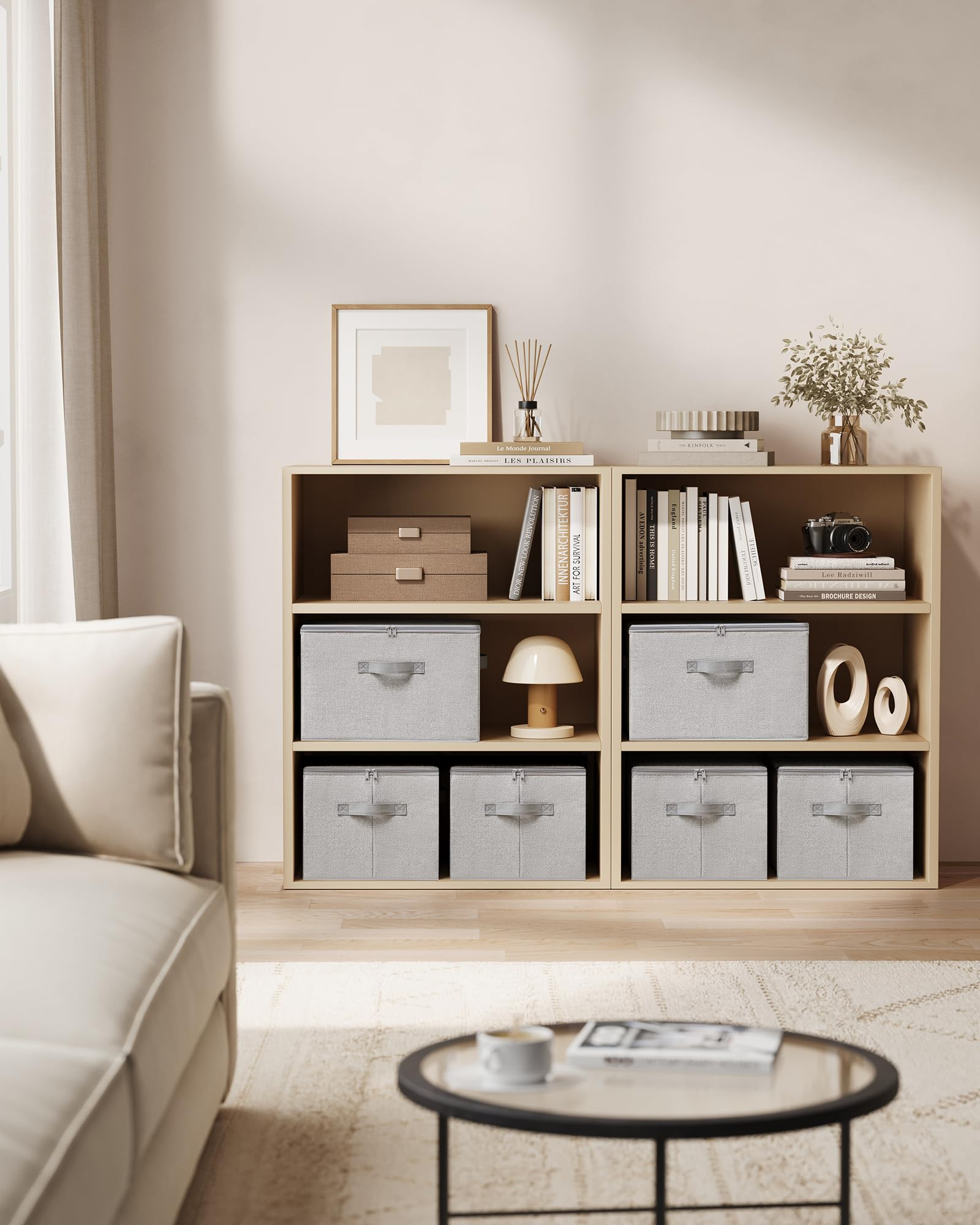 Scaffali in legno con scatole portaoggetti grigio chiaro, libri e decorazioni accanto a un divano.