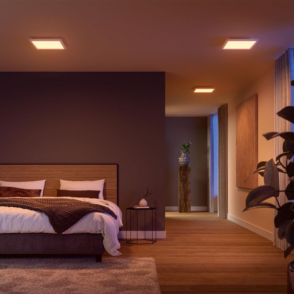 Camera da letto calda con letto in legno, cuscini bianchi, coperta lavorata a maglia, plafoniere quadrate e corridoio.