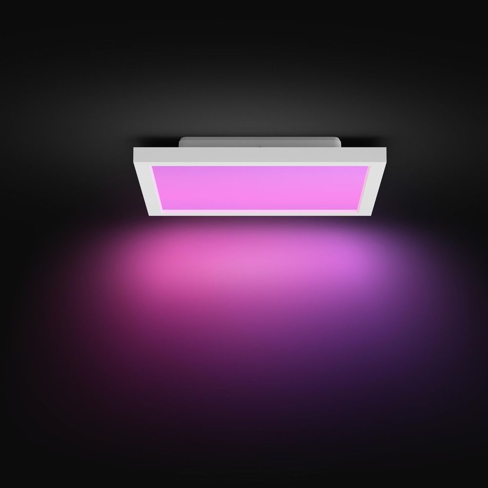 Una lampada da soffitto bianca e rettangolare emette una vivace luce rosa e viola su sfondo scuro.