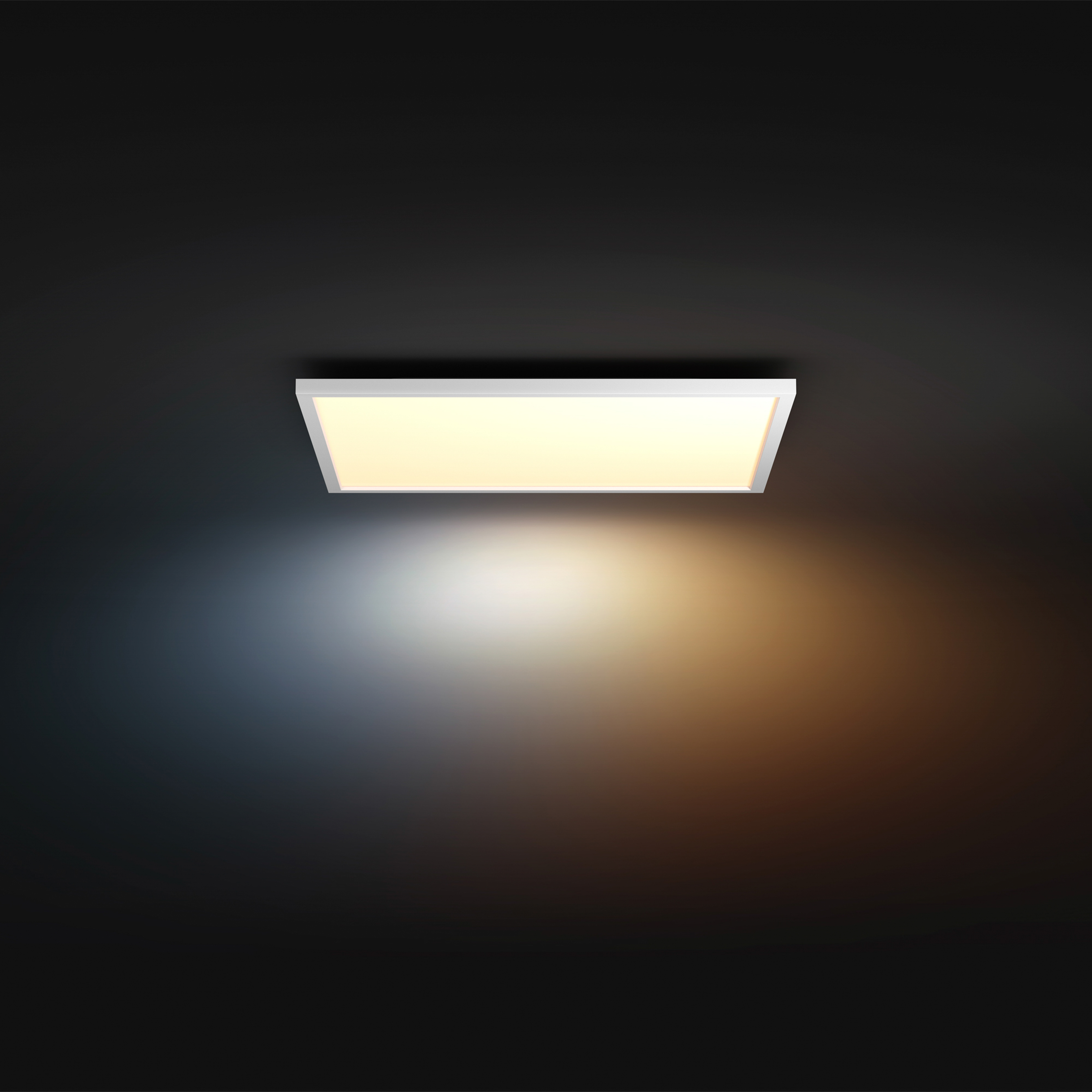 Un pannello luminoso da soffitto rettangolare brilla su sfondo scuro, emettendo una luce bianca tenue e arancione calda.