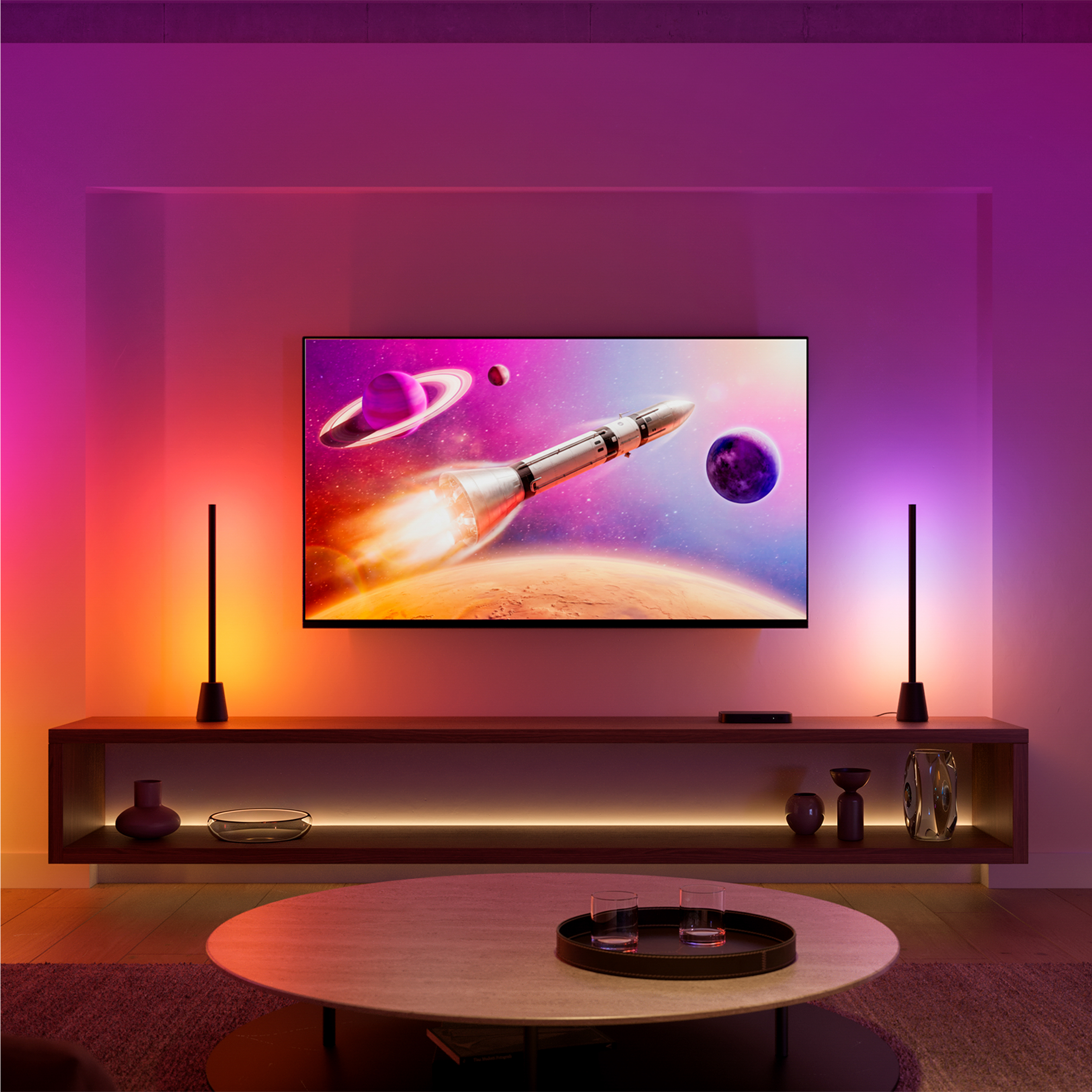 Soggiorno con TV che mostra lo spazio, illuminato da luci ambientali colorate e due lampade alte.