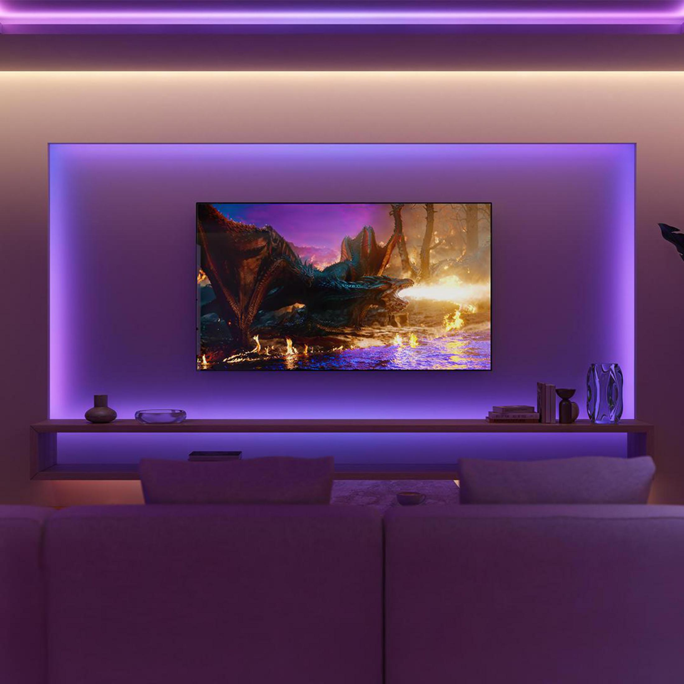 Un soggiorno mostra una TV con una scena di drago, incorniciata da un'illuminazione ambientale viola.