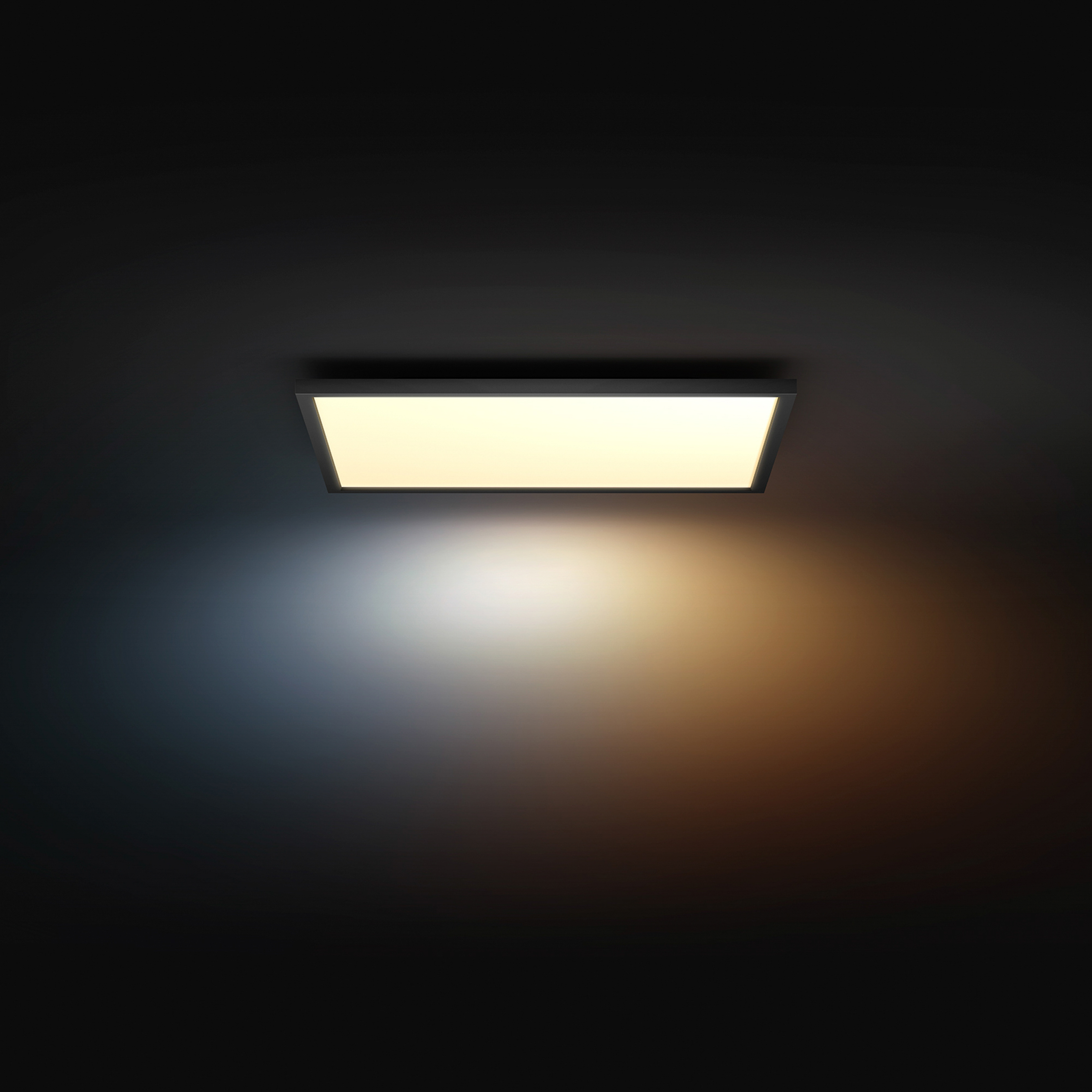 Una plafoniera rettangolare emette luce calda e fredda contro una parete scura.