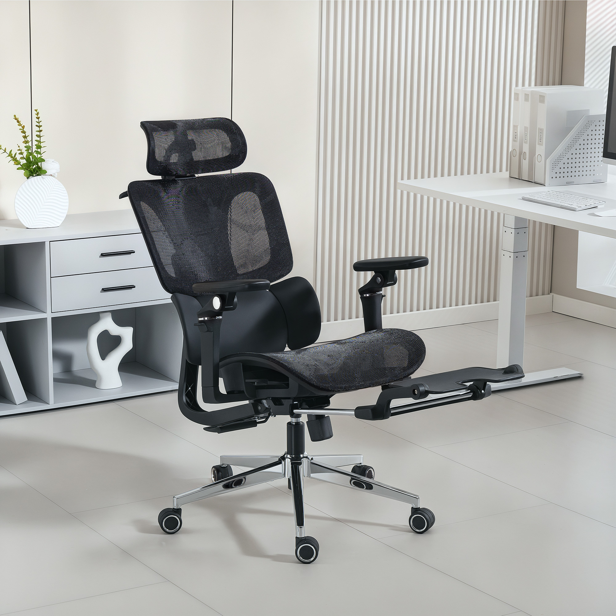 Sedia da ufficcio ergonomica nera con schienale in rete, poggiatesta e poggiapiedi in un ufficio moderno.