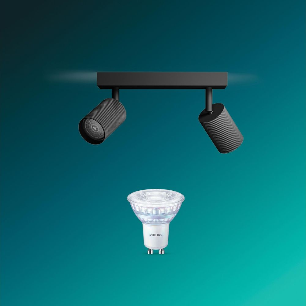 Eine schwarze Doppeldeckenleuchte vor tealgrünem Hintergrund, darunter eine schwebende Philips LED-Lampe.