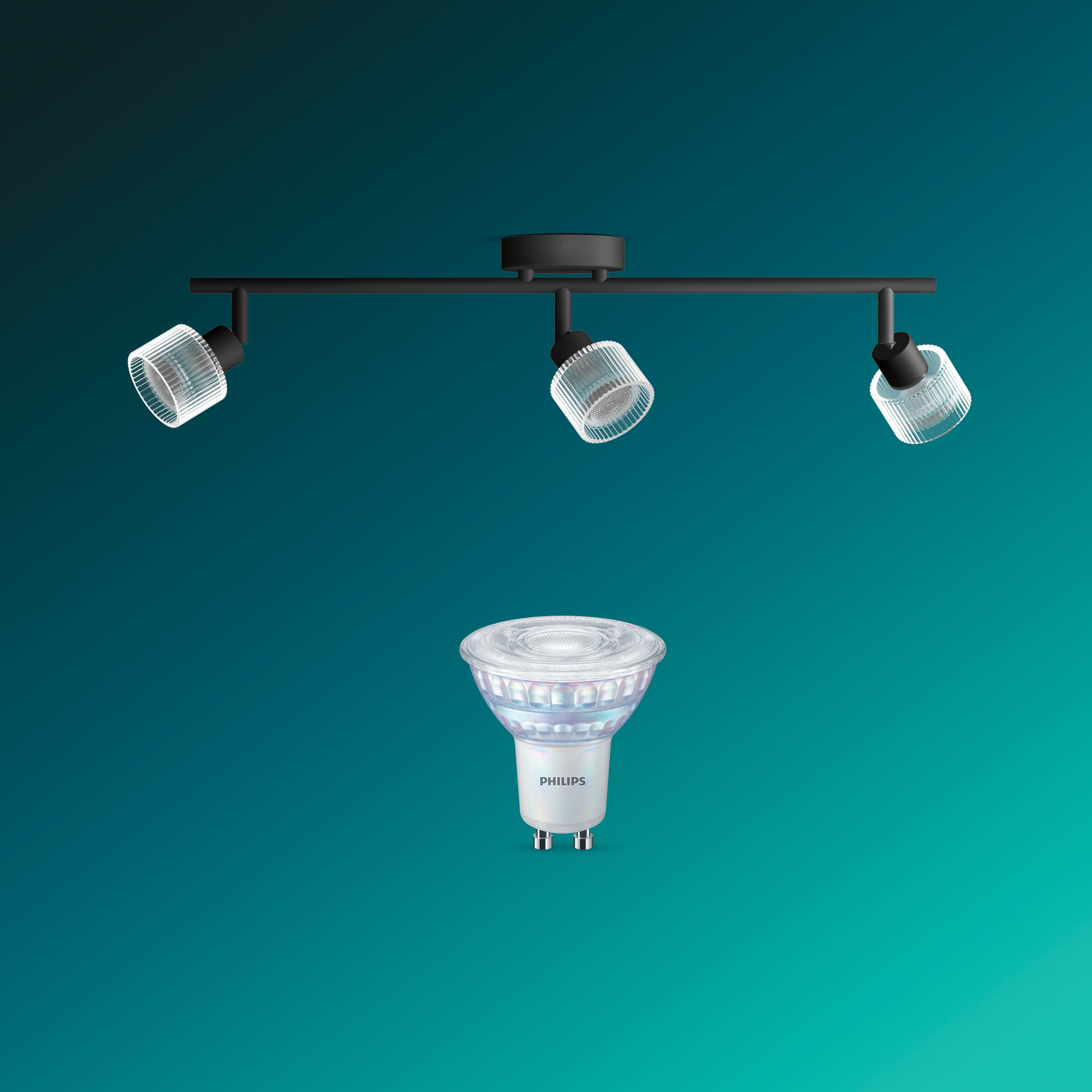 Eine schwarze Deckenleuchte mit drei gerippten Glasschirmen und eine einzelne Philips LED-Lampe davor auf türkisfarbenem Grund.