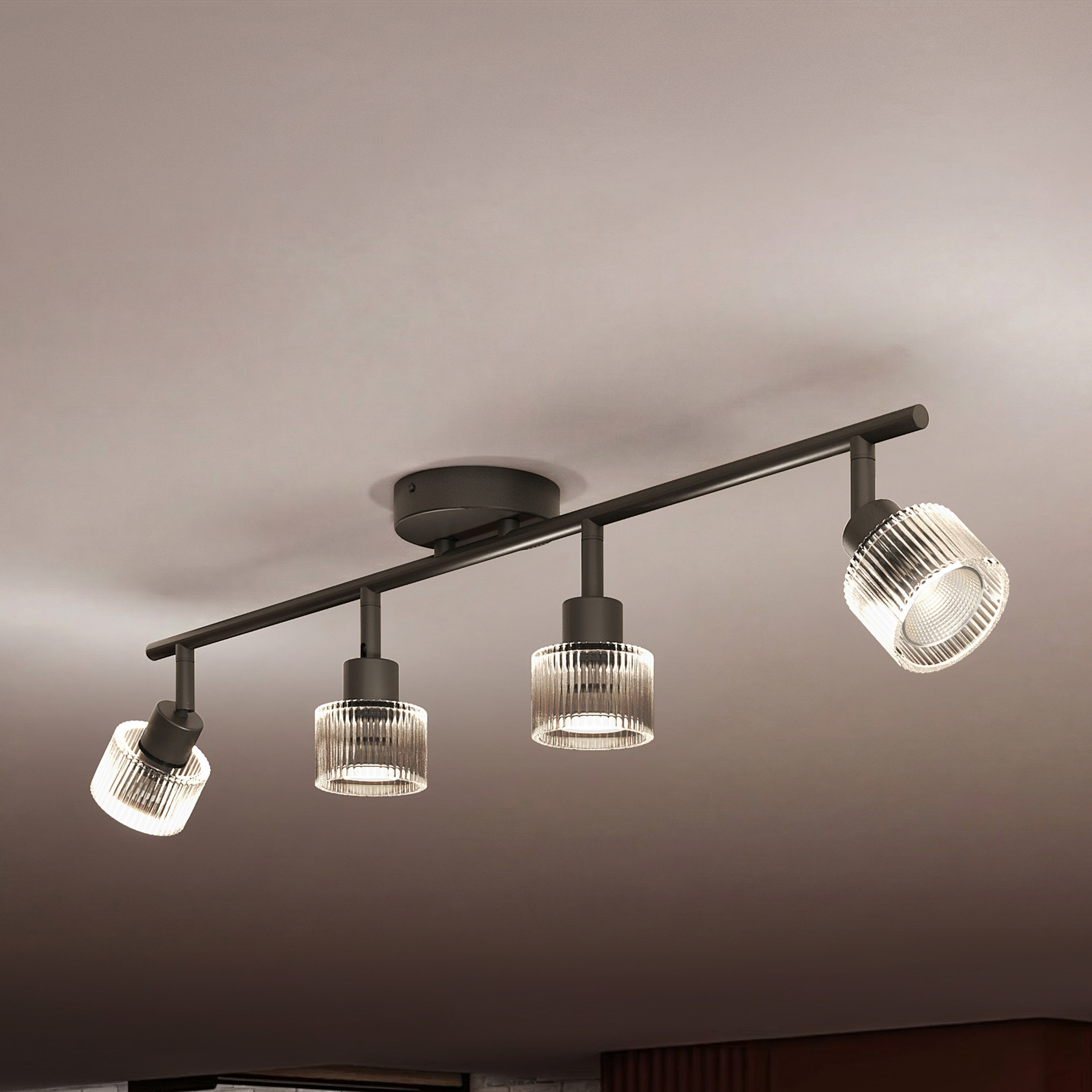 Eine schwarze Deckenleuchte mit vier verstellbaren, gerippten Glas-Spotlights an einer Stange.