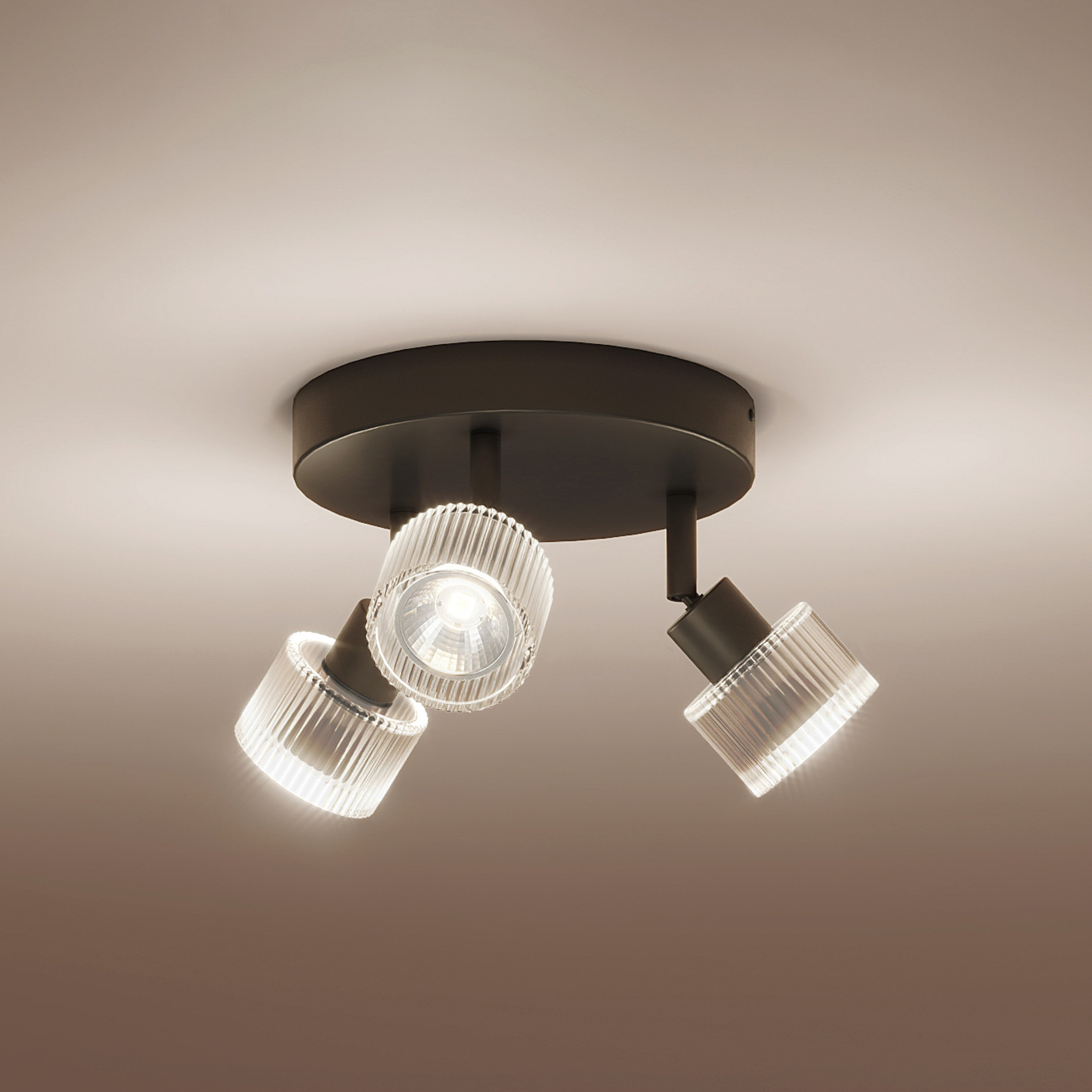 Eine schwarze Deckenleuchte mit drei gerippten Glasschirmen strahlt helles Licht an die weiße Decke.