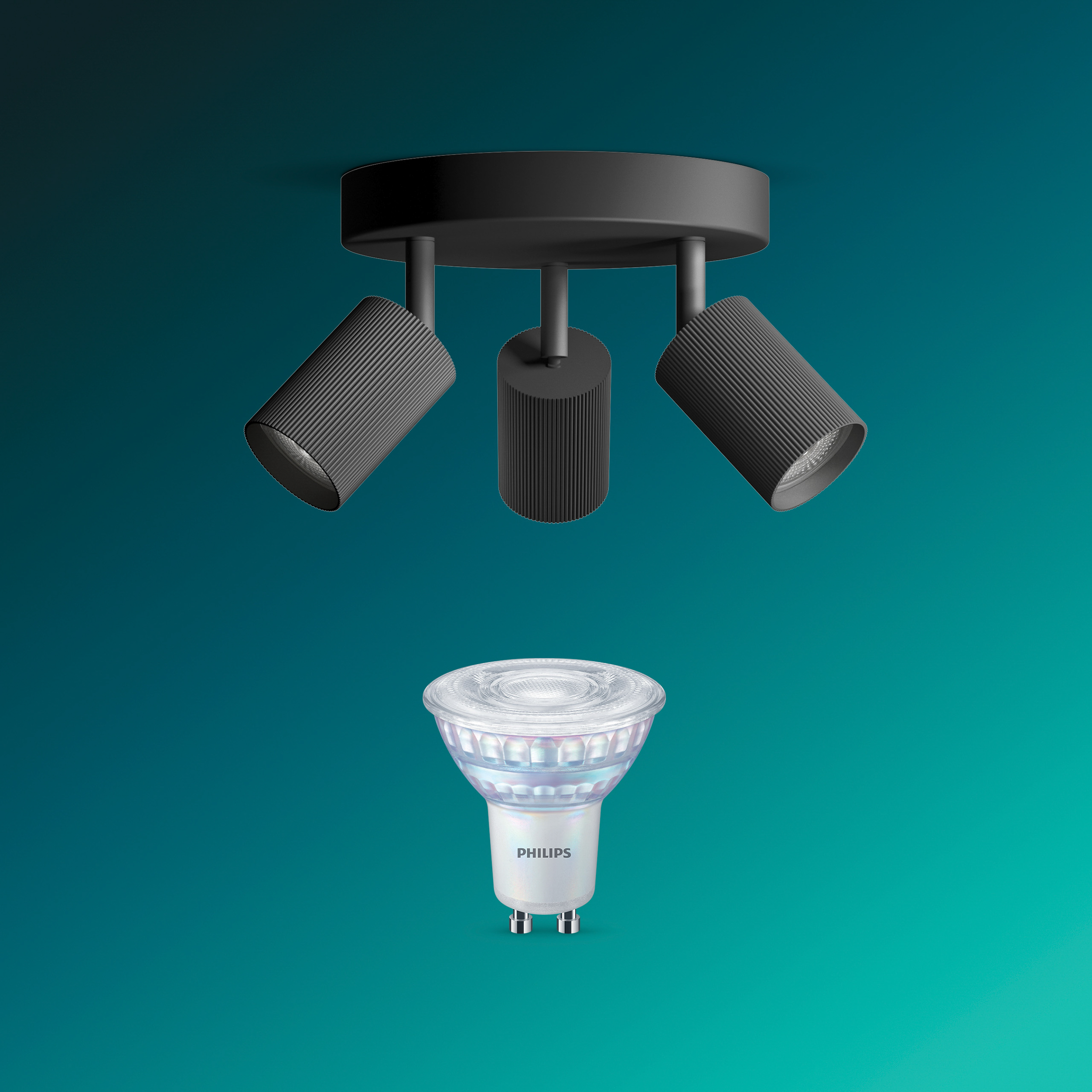 Ein schwarzer Deckenstrahler mit drei Lampen und eine separate Philips LED-Glühbirne vor einem türkis-grünen Hintergrund.