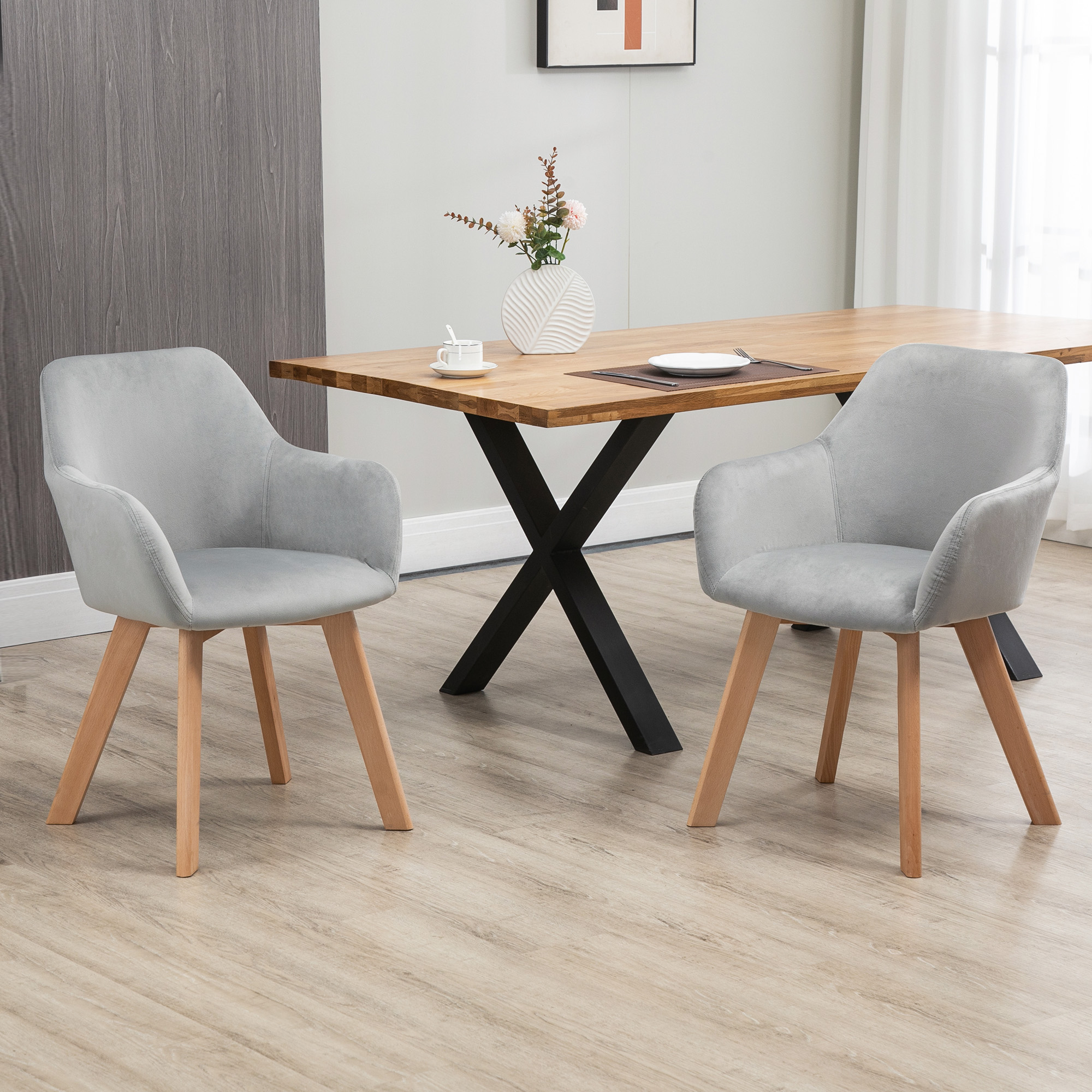 Due poltroncine grigio chiaro con gambe in legno di fronte a un tavolo da pranzo in legno.