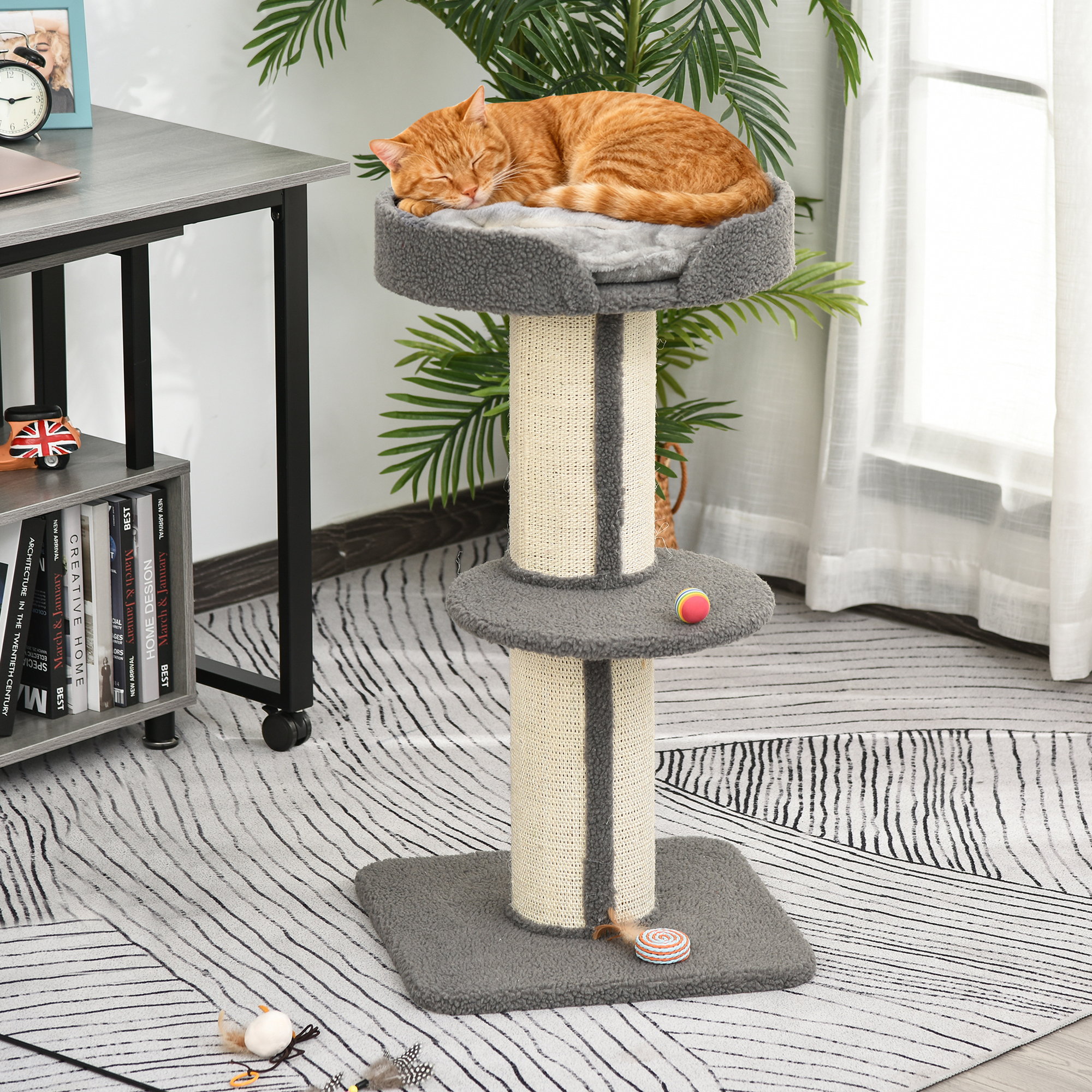 Un gatto arancione che dorme su un tiragraffi grigio in una stanza con tappeto fantasia.