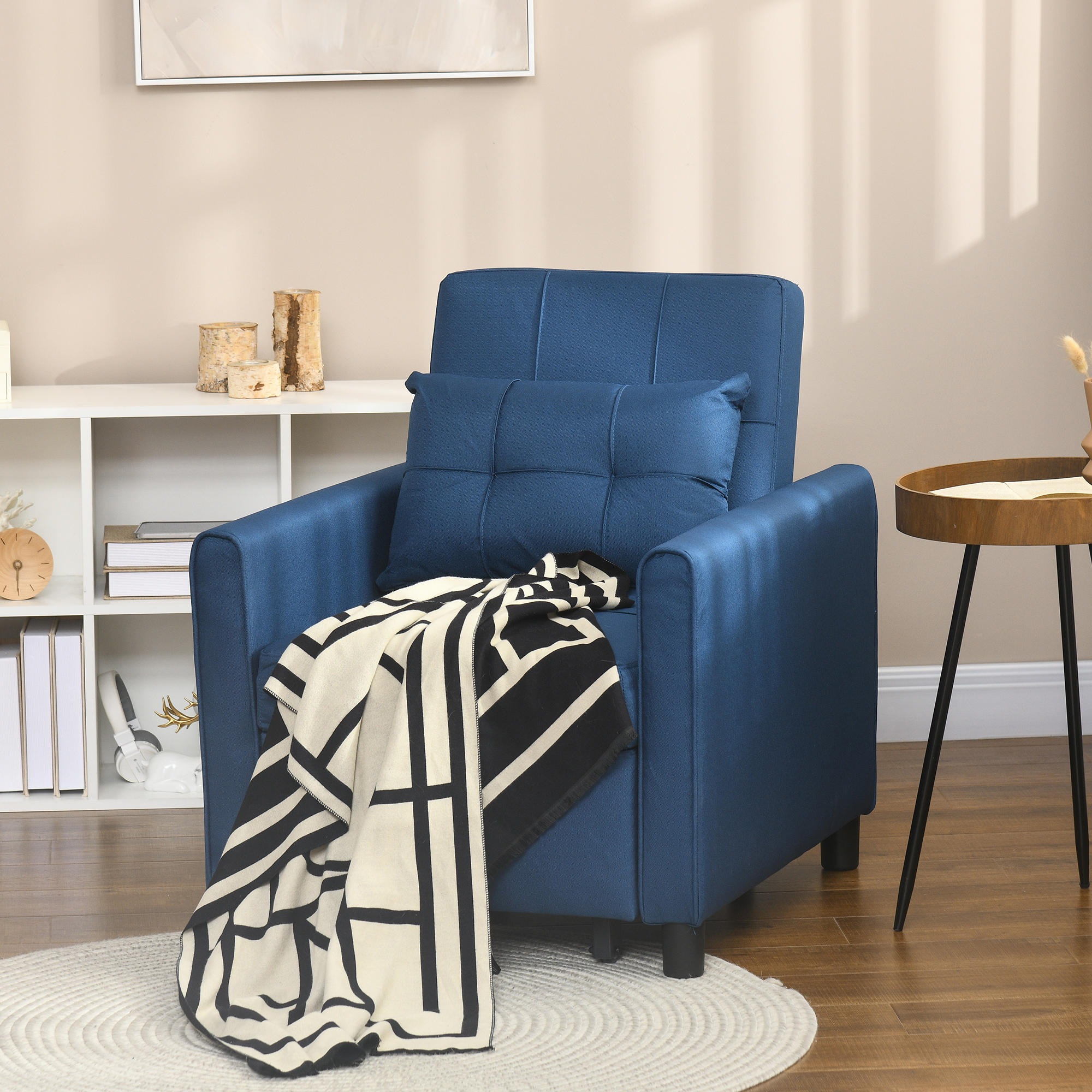 Poltrona blu con cuscino e coperta bianco-nera su tappeto chiaro davanti a parete beige.