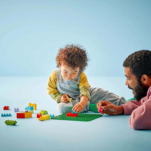 Un bambino piccolo e un adulto giocano con blocchi colorati su sfondo azzurro.