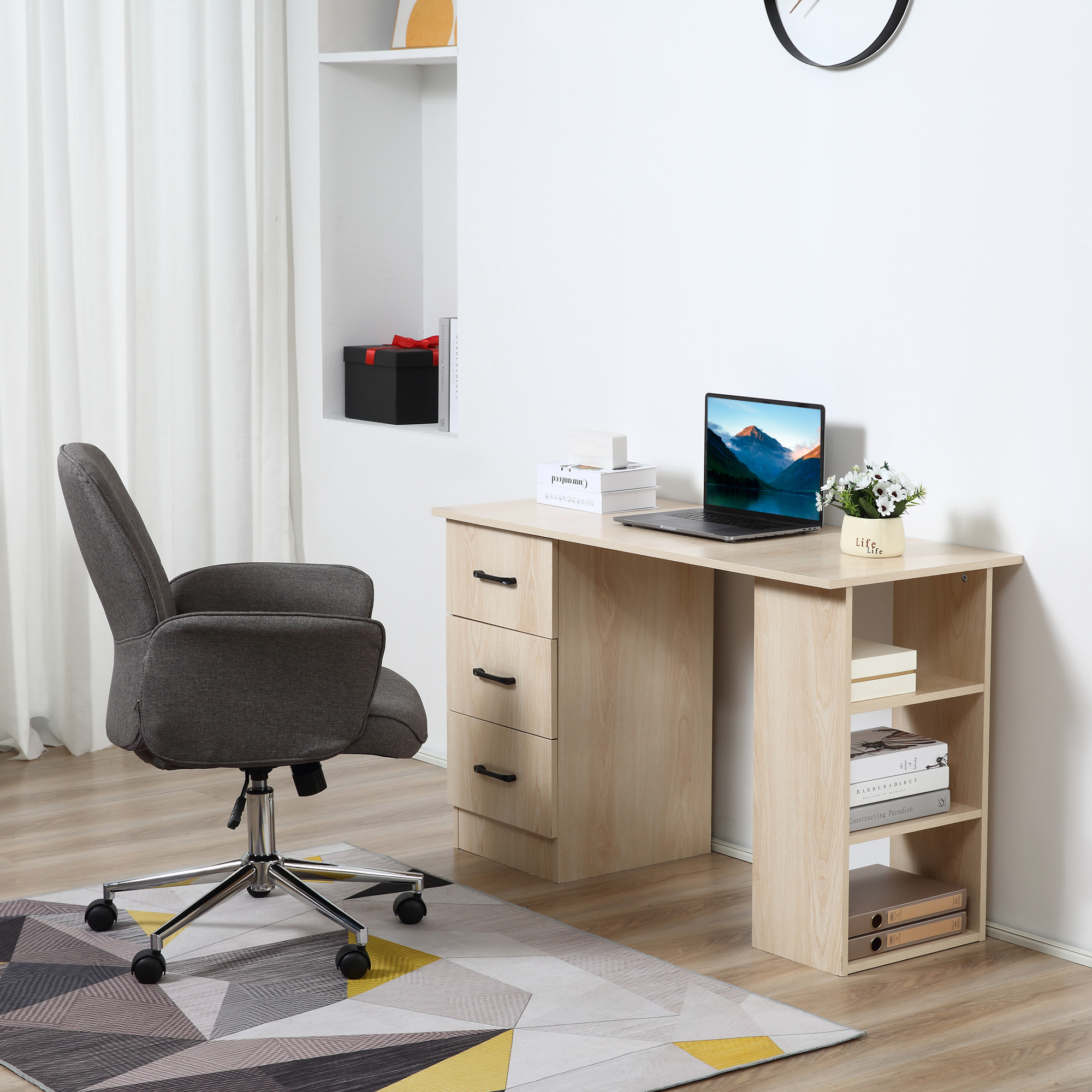 Una scrivania in legno chiaro con cassetti, ripiani e un laptop, abbinata a una sedia da ufficio grigia.