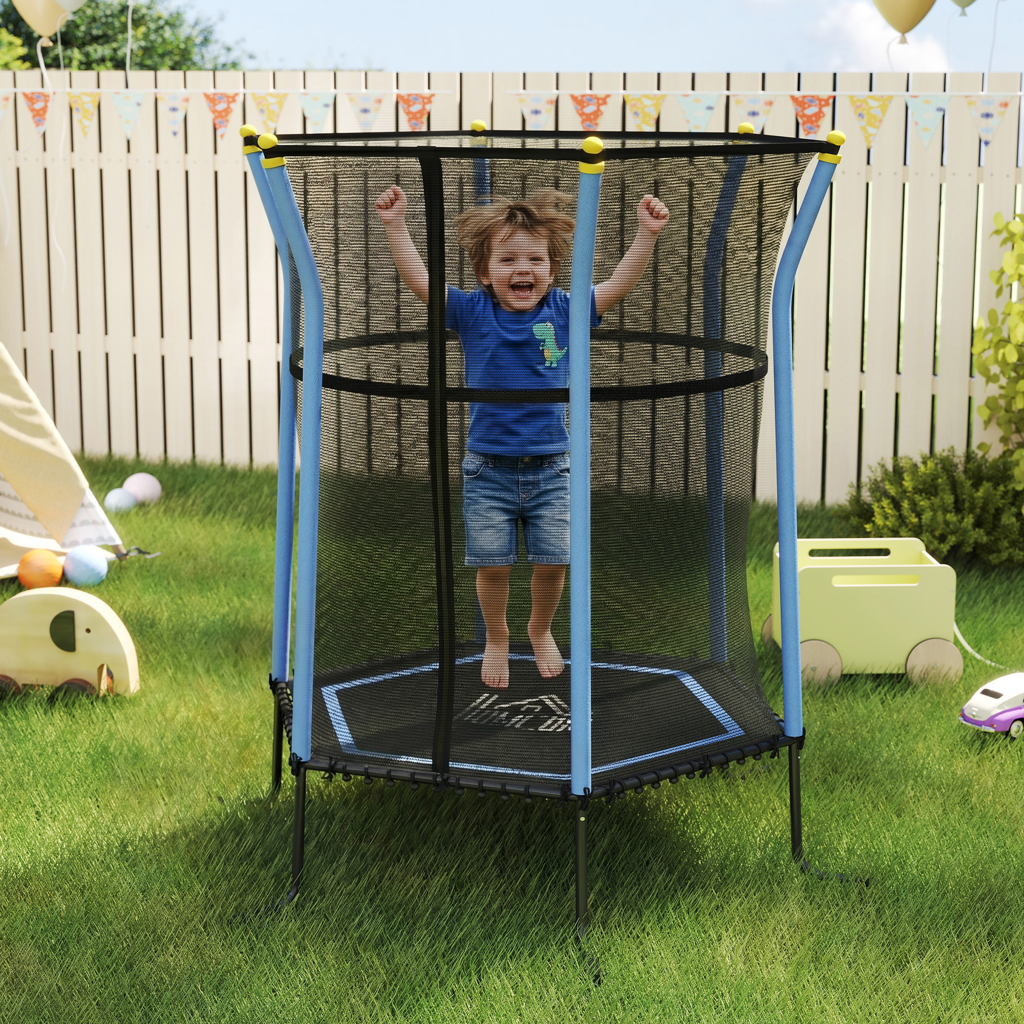Un bambino felice salta dentro un tappeto elastico da giardino blu con rete di protezione davanti a una staccionata.