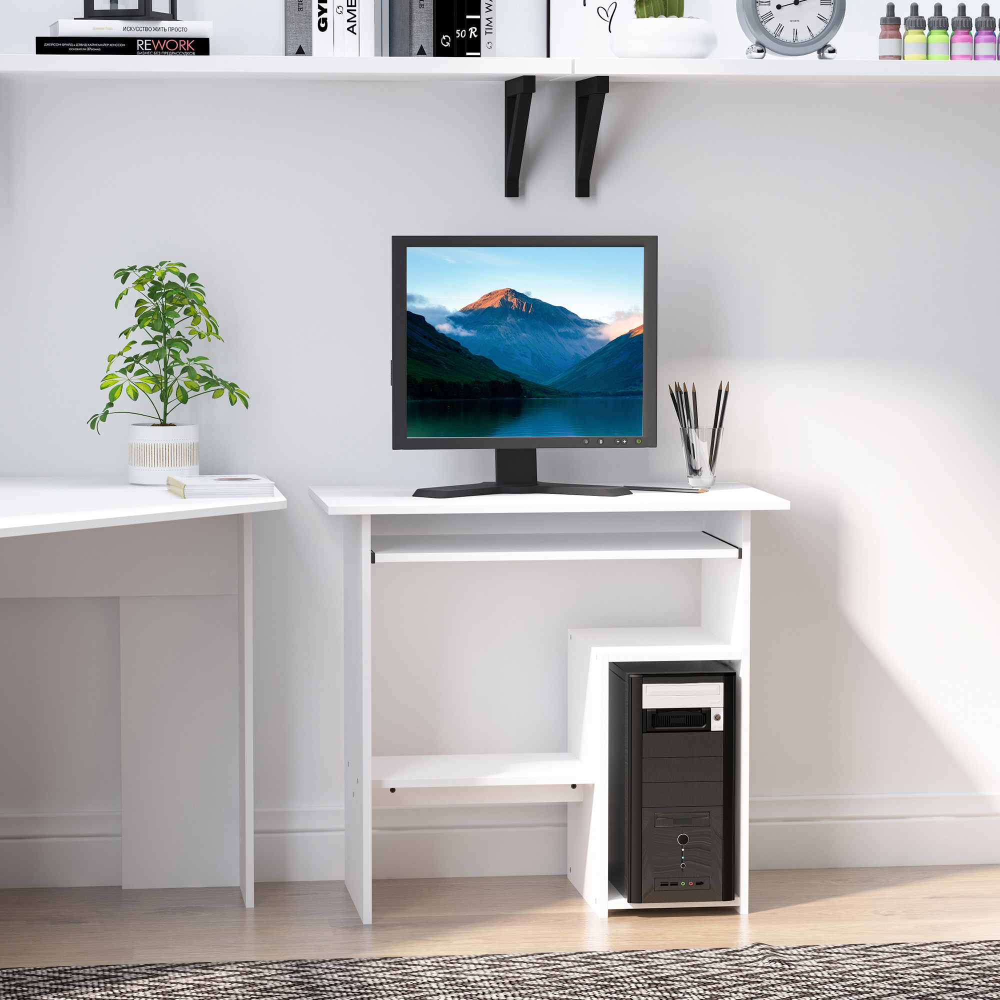 Una scrivania bianca per computer con monitor, torre PC, penne e una piccola pianta contro una parete bianca.
