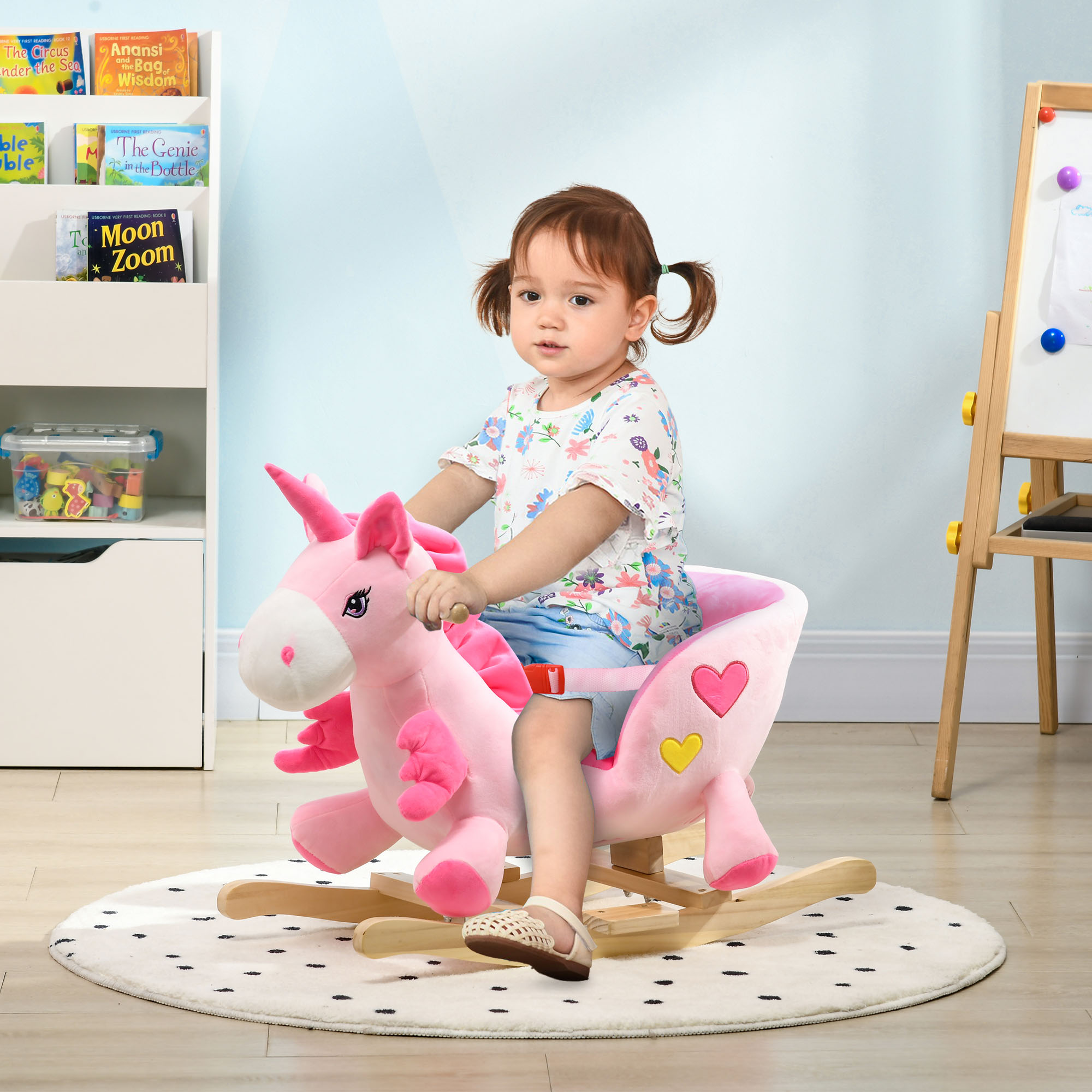 Bambina che cavalca un unicorno a dondolo di peluche rosa in una cameretta.