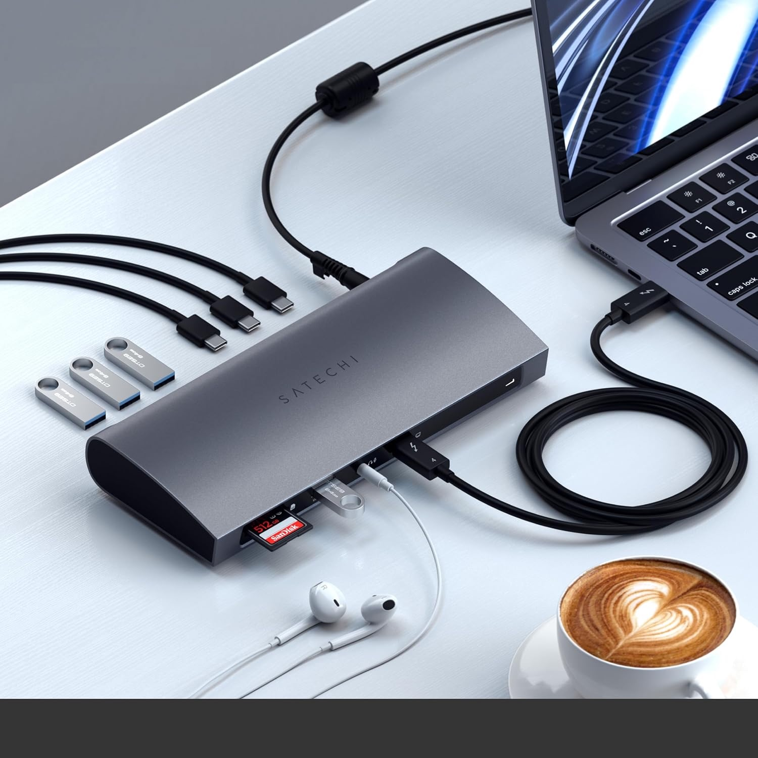 Grauer Satechi-USB-Hub mit Kabeln, SD-Karte und Kaffeetasse auf weißem Tisch.