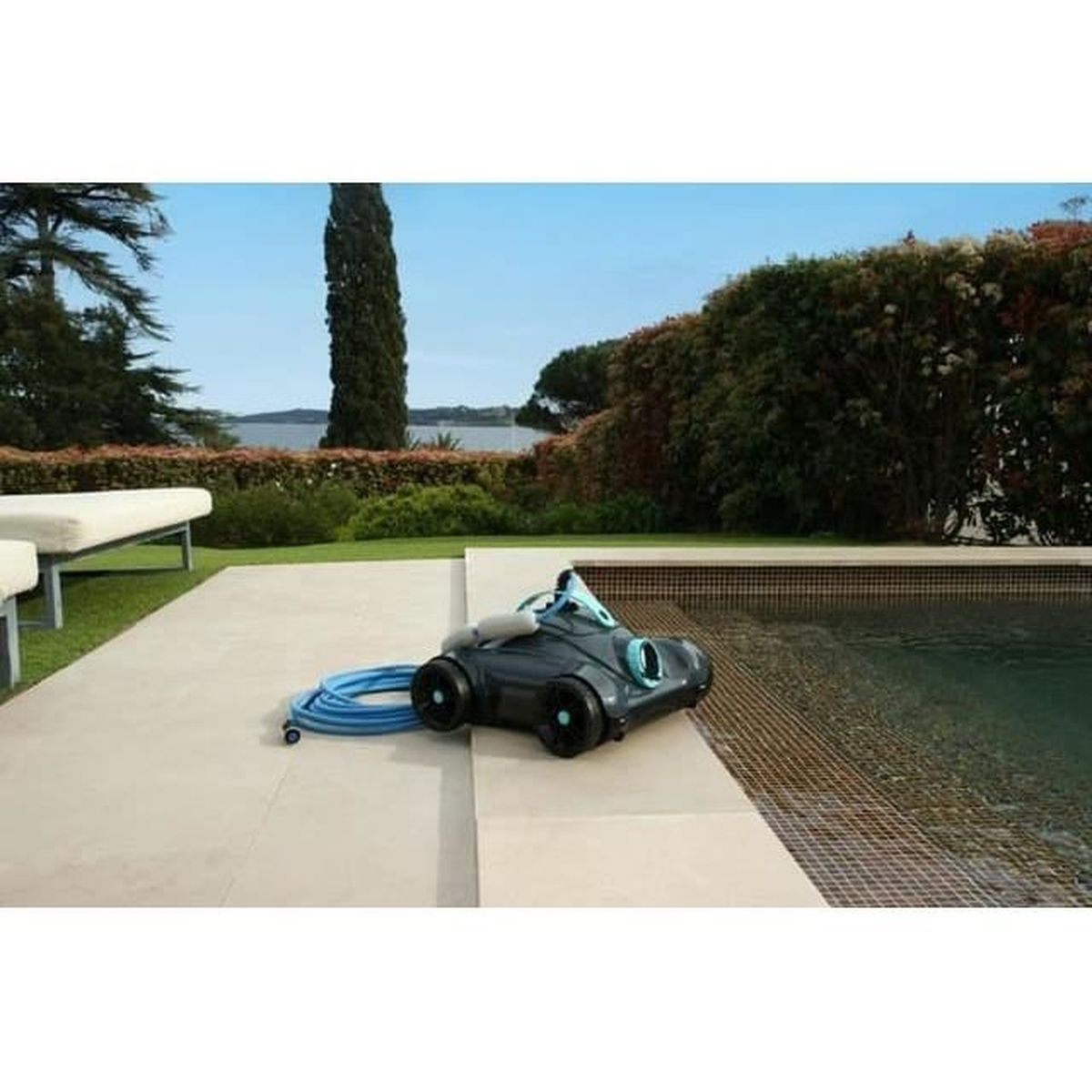 Un pulitore per piscina grigio con tubo blu sul bordo di una piscina all'aperto.