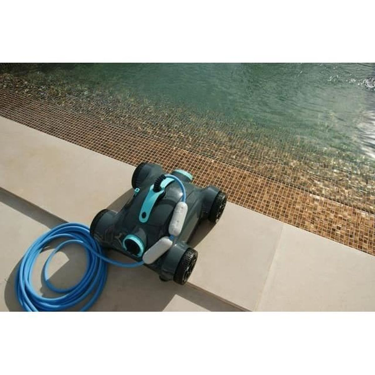 Un pulitore per piscina grigio con un tubo blu si trova sul bordo di una piscina piastrellata.