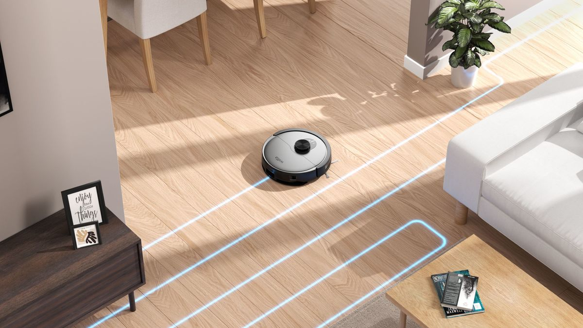 Un robot aspirapolvere pulisce un pavimento in legno, guidato da linee blu luminose in un luminoso soggiorno.