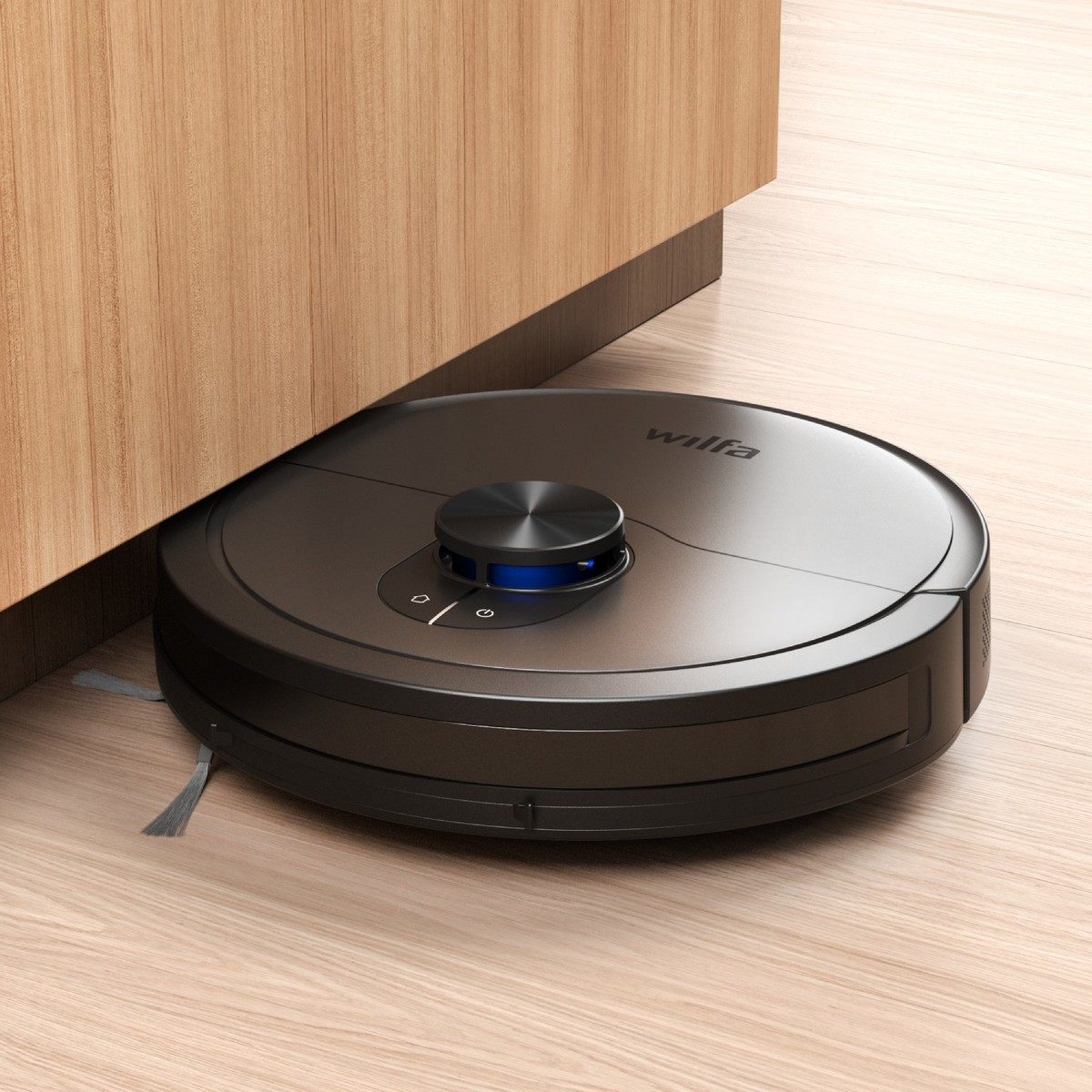 Un robot aspirapolvere nero su pavimento in legno pulisce sotto i mobili.