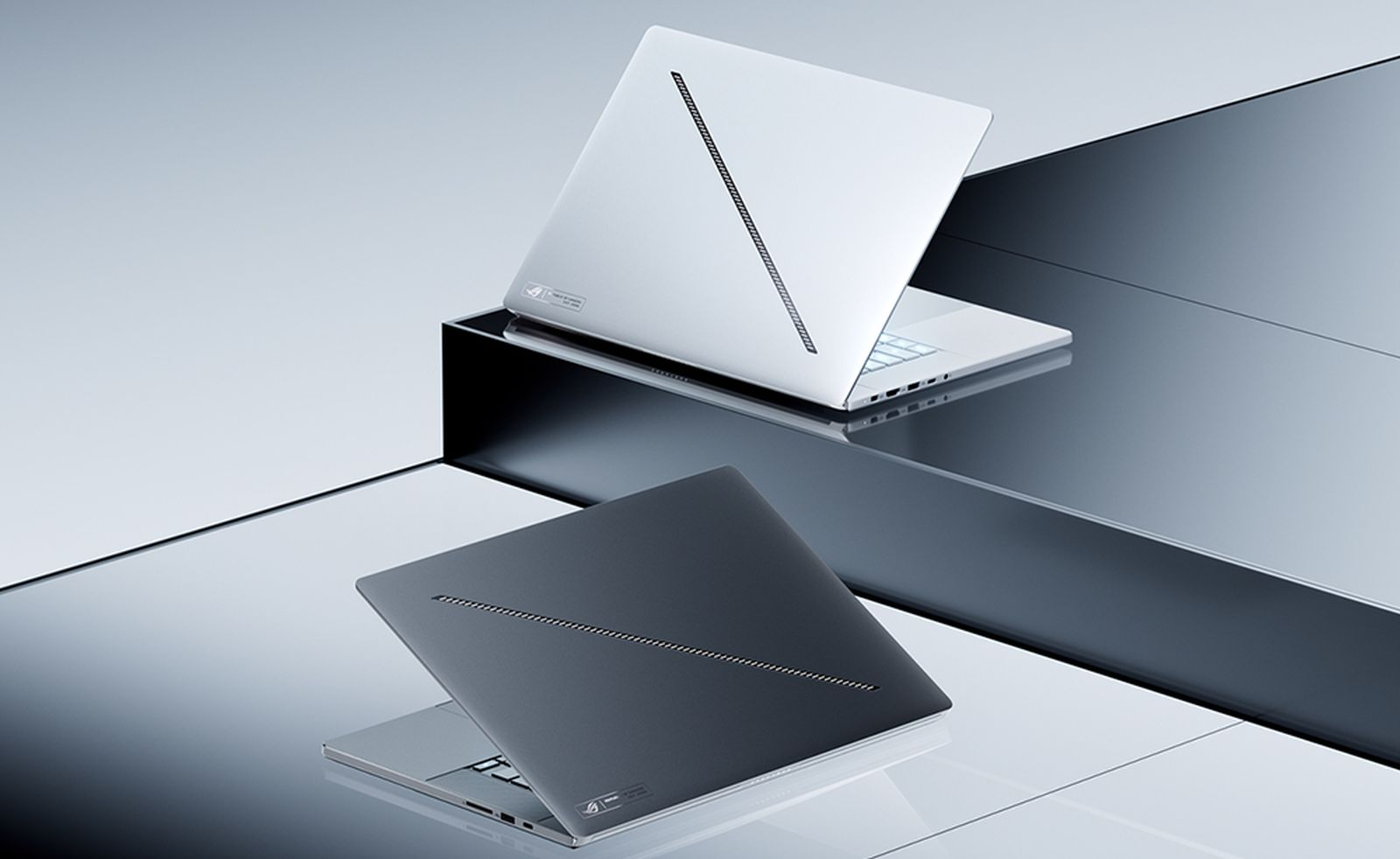 Zwei schlanke Laptops mit diagonalem LED-Streifen auf dem Deckel stehen auf einer reflektierenden Oberfläche.